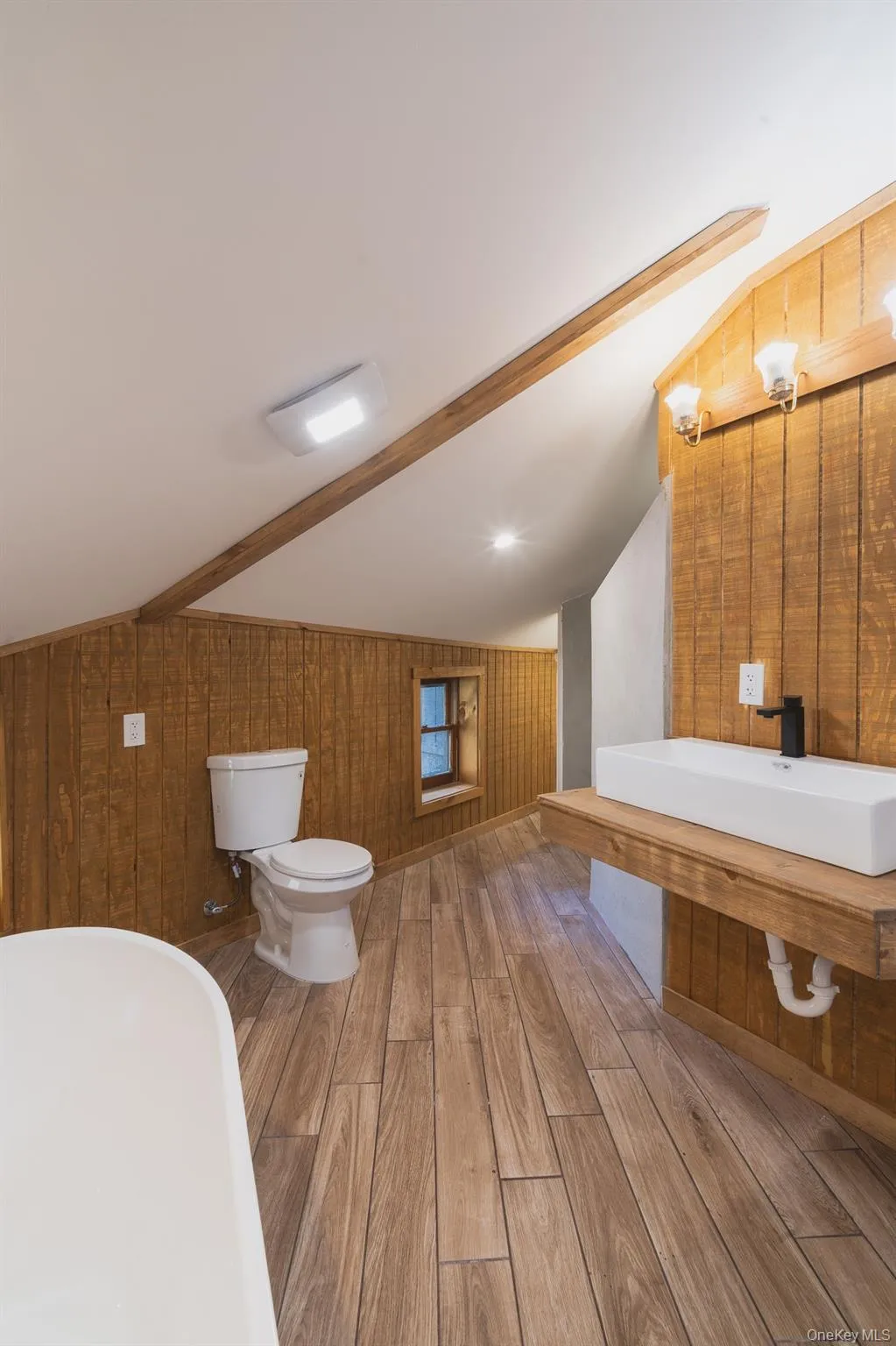 Bathroom featuring wood walls, wood finished floors, a freestanding bath, and vanity Bathroom featuring wood walls, wood finished floors, a freestanding bath, and vanity