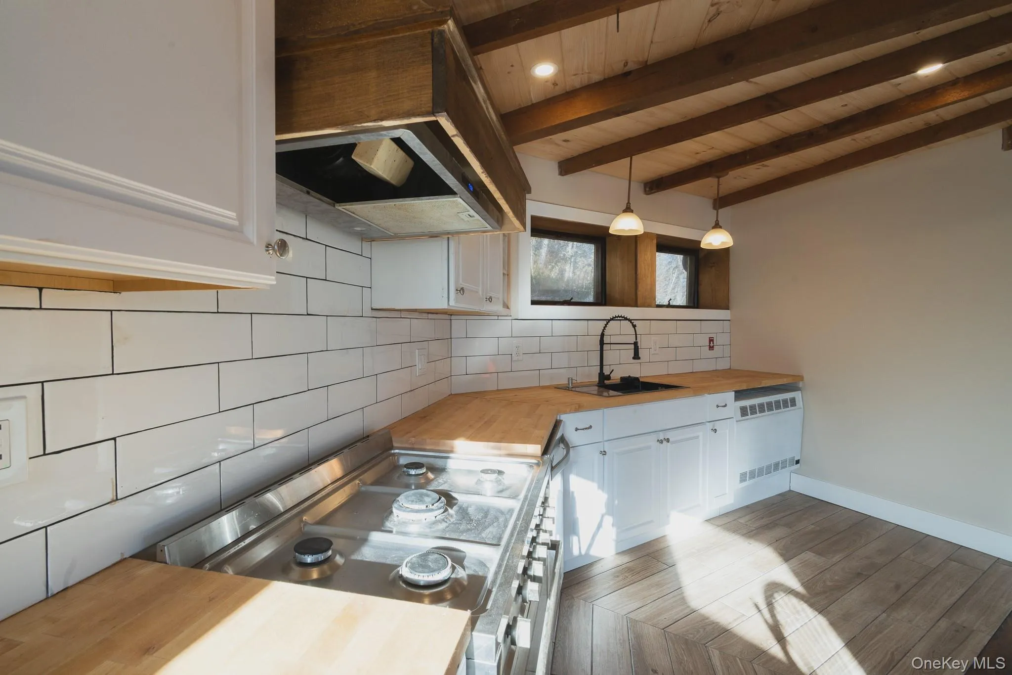 Kitchen featuring wood counters, white cabinetry, decorative backsplash, stainless steel range oven, and ventilation hood Kitchen featuring wood counters, white cabinetry, decorative backsplash, stainless steel range oven, and ventilation hood