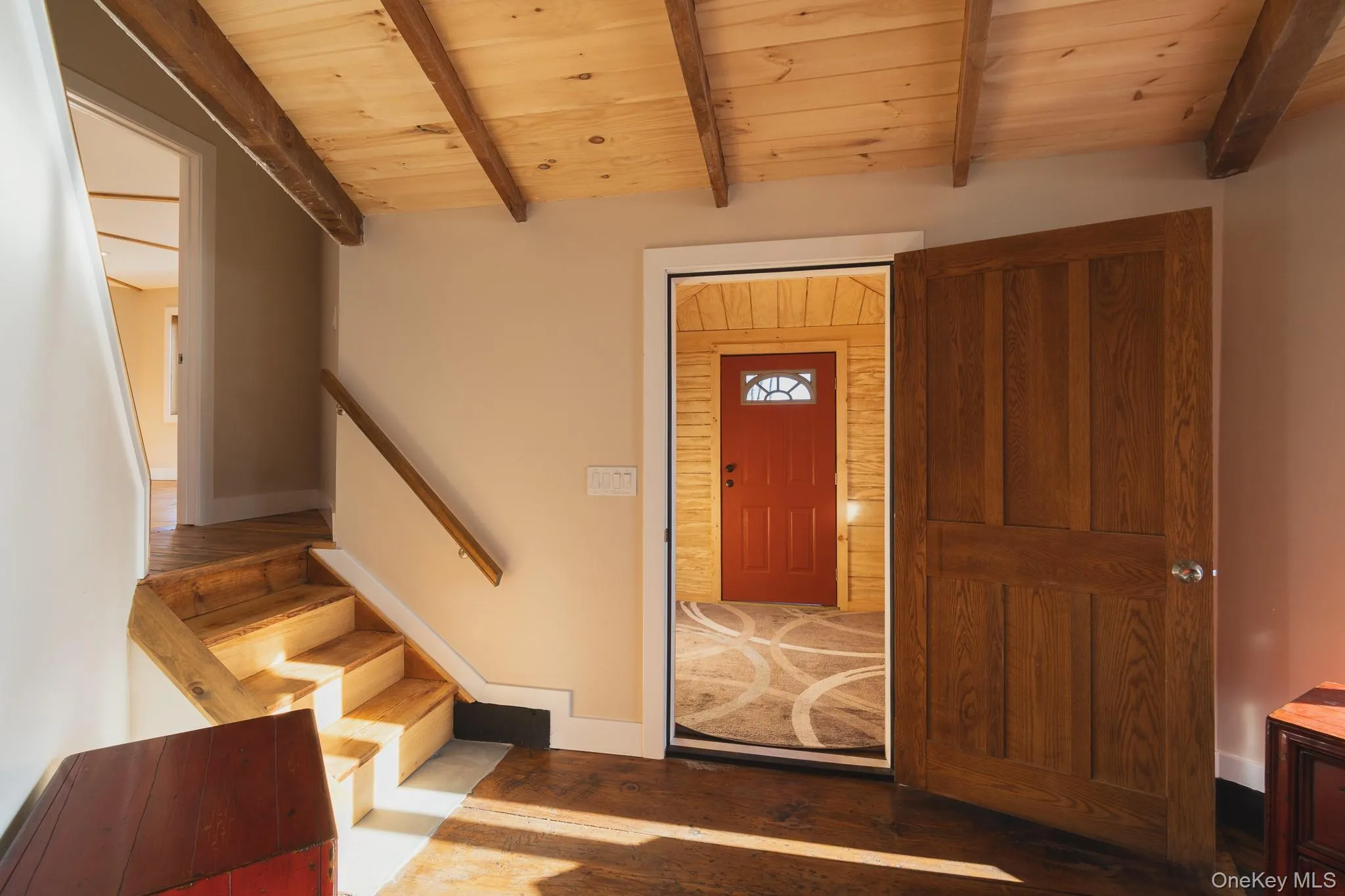 Entryway with dark wood-type flooring, a wood ceiling with exposed beams, and stairs Entryway with dark wood-type flooring, a wood ceiling with exposed beams, and stairs