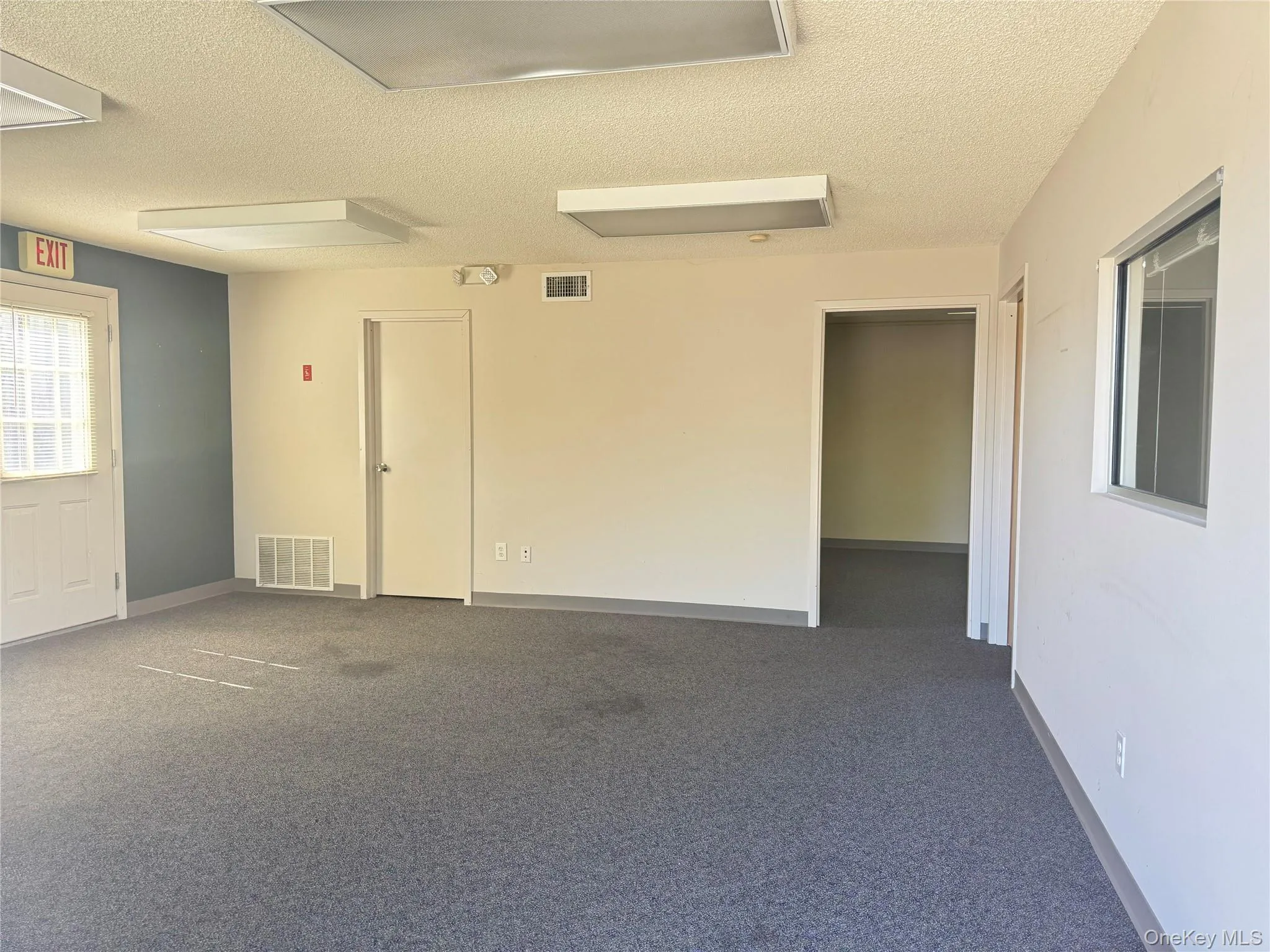 Unfurnished room featuring a textured ceiling and dark carpet Unfurnished room featuring a textured ceiling and dark carpet
