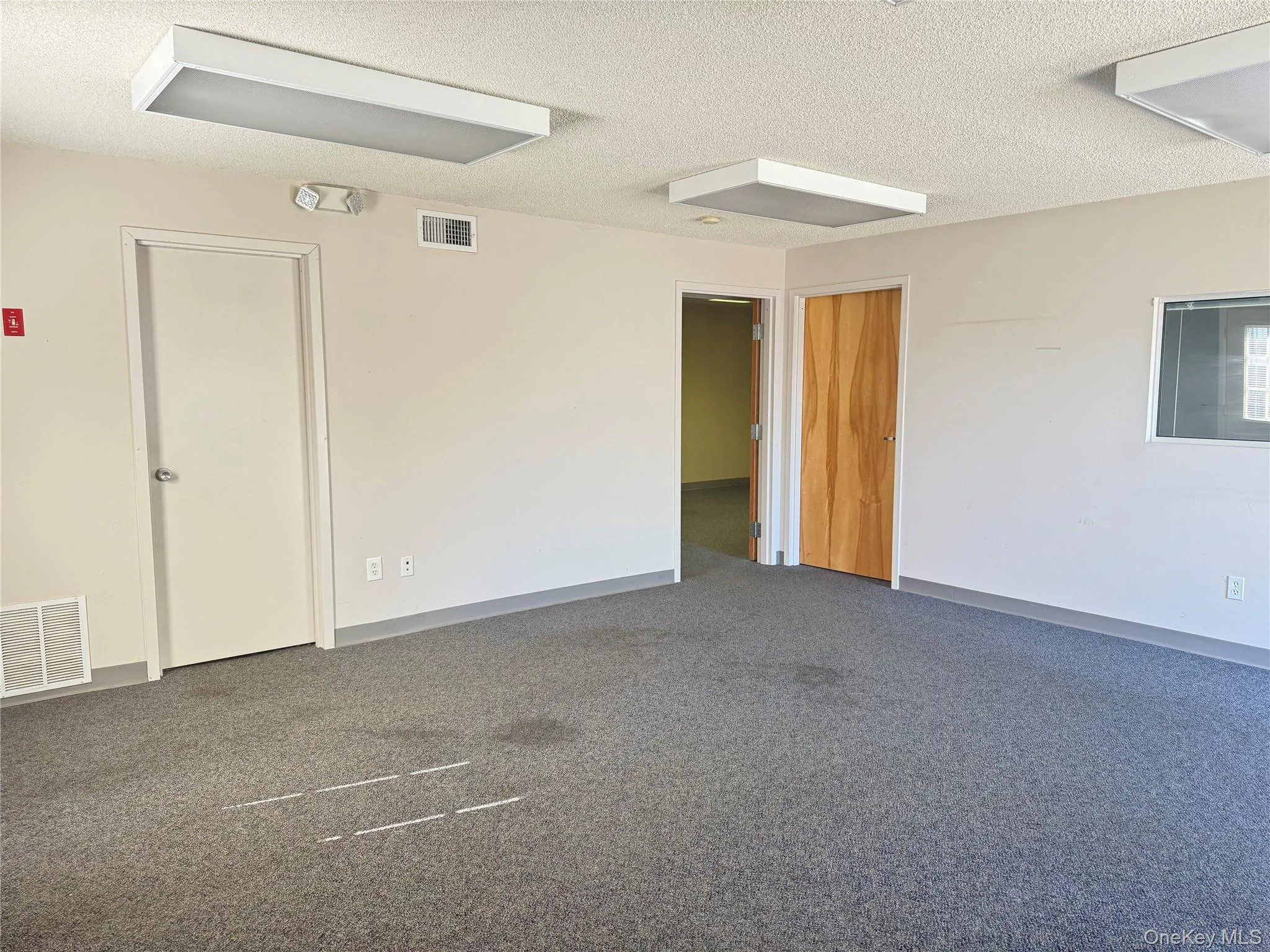 Empty room with a textured ceiling and dark carpet Empty room with a textured ceiling and dark carpet