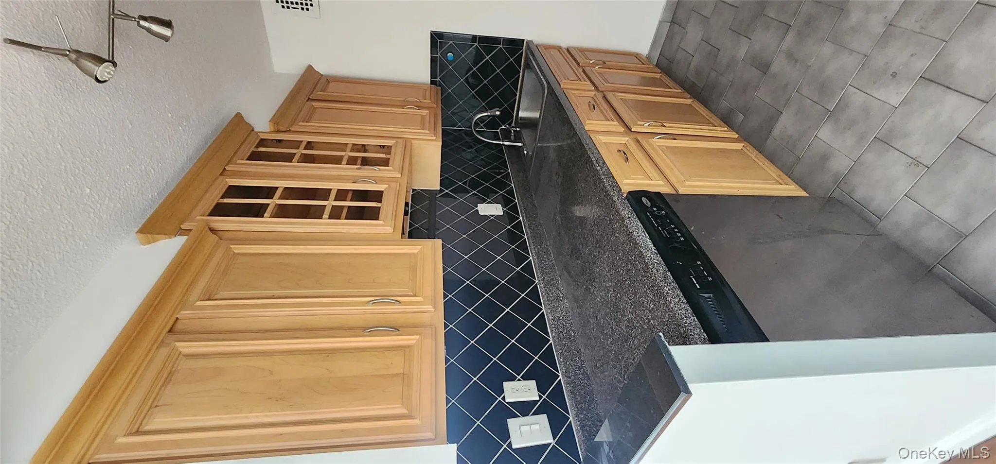 Kitchen with backsplash, dishwasher, a textured ceiling, glass insert cabinets, and dark stone counters Kitchen with backsplash, dishwasher, a textured ceiling, glass insert cabinets, and dark stone counters