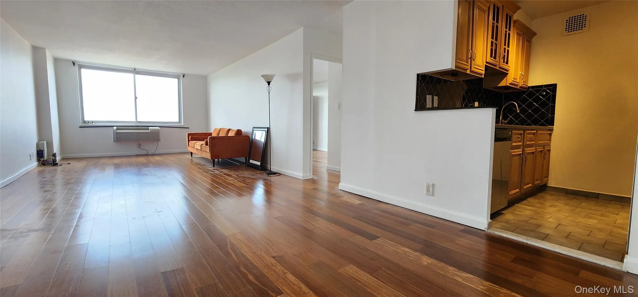 Living room with light wood-type flooring, a wall mounted air conditioner, and lofted ceiling Living room with light wood-type flooring, a wall mounted air conditioner, and lofted ceiling