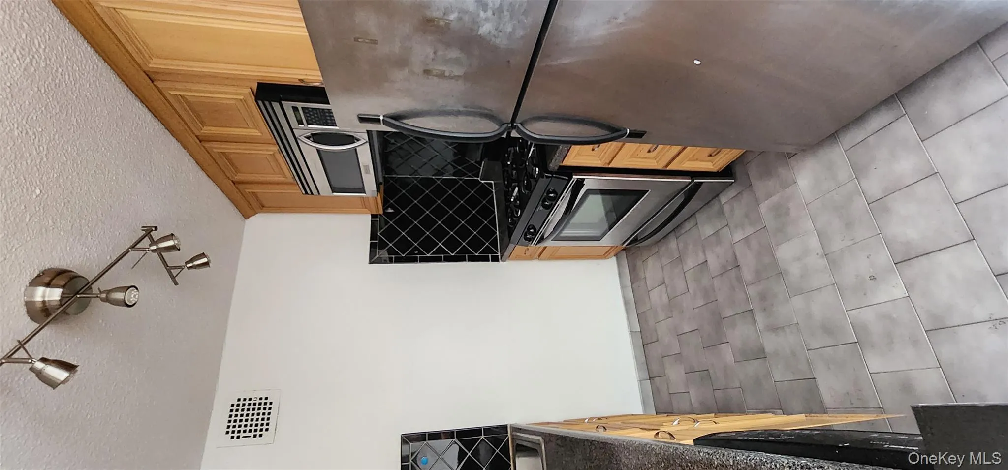 Kitchen with stainless steel appliances, tasteful backsplash, light brown cabinetry, a textured ceiling, and track lighting Kitchen with stainless steel appliances, tasteful backsplash, light brown cabinetry, a textured ceiling, and track lighting