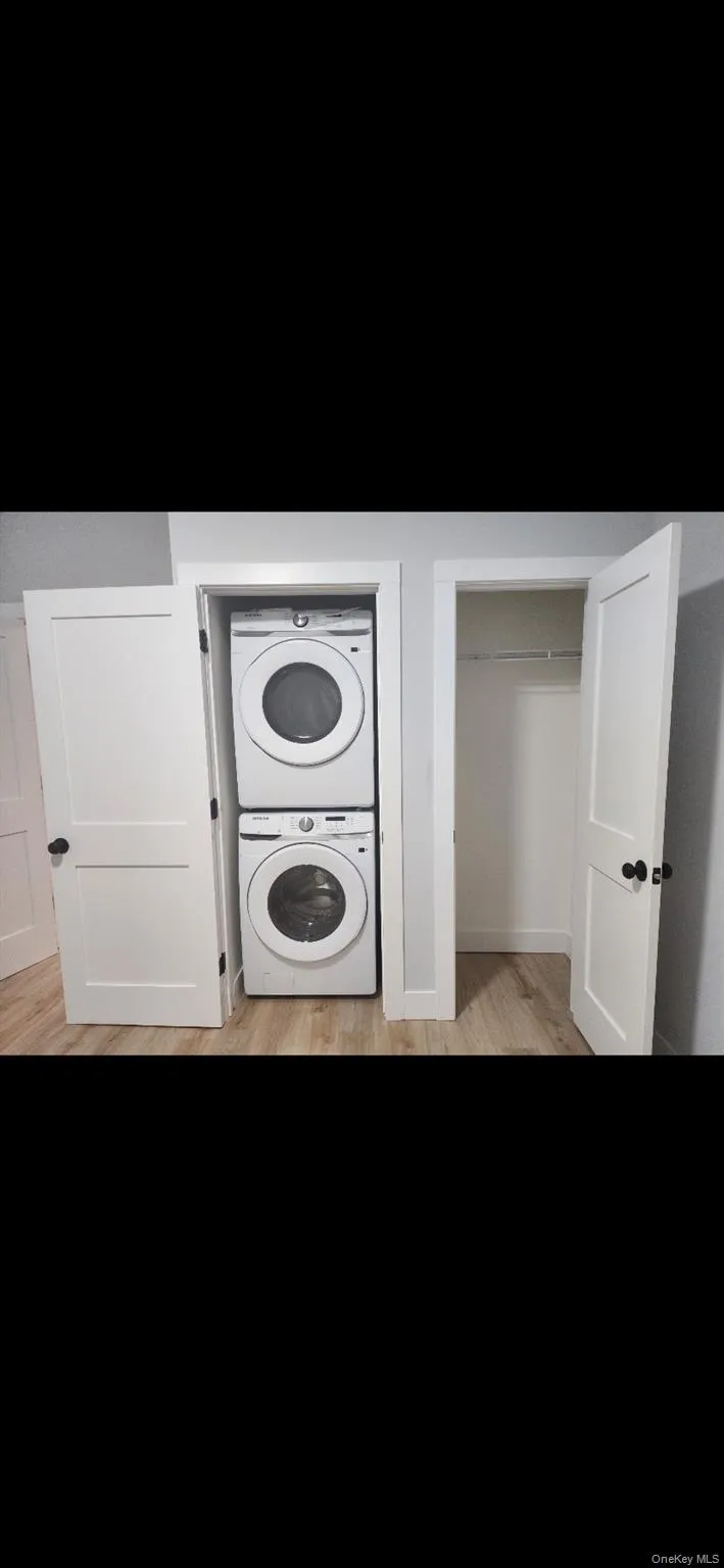 Laundry area with stacked washer and clothes dryer and light wood-style floors Laundry area with stacked washer and clothes dryer and light wood-style floors