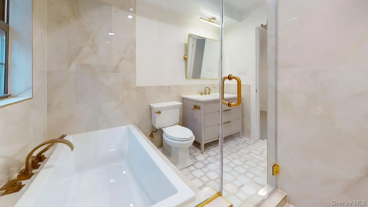 Full bath with a bath, vanity, and tile walls Full bath with a bath, vanity, and tile walls