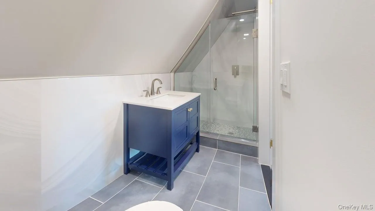 Bathroom with vanity, vaulted ceiling, a stall shower, and dark tile patterned flooring Bathroom with vanity, vaulted ceiling, a stall shower, and dark tile patterned flooring