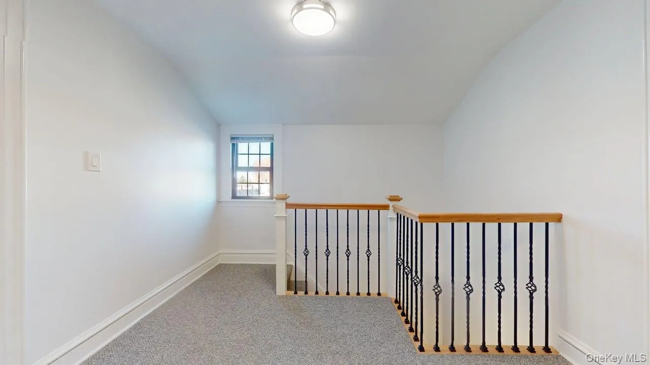 Corridor featuring vaulted ceiling, carpet floors, and an upstairs landing Corridor featuring vaulted ceiling, carpet floors, and an upstairs landing