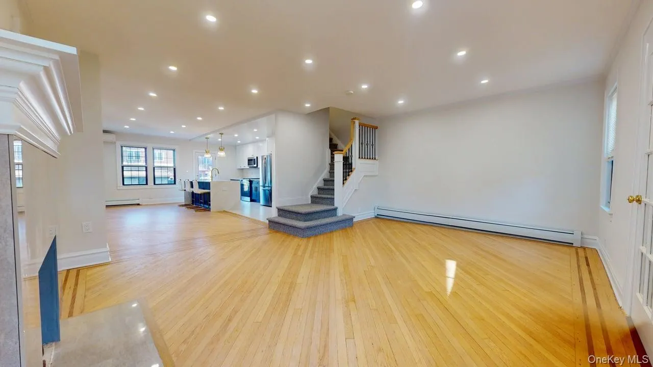 Unfurnished living room featuring recessed lighting, baseboard heating, light wood-style flooring, and stairway Unfurnished living room featuring recessed lighting, baseboard heating, light wood-style flooring, and stairway