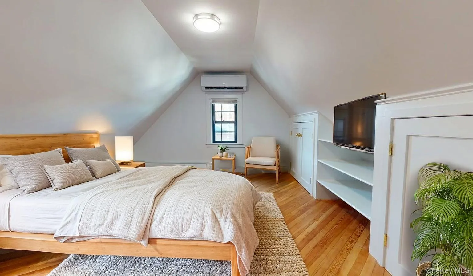 Bedroom featuring light wood-type flooring, vaulted ceiling, and an AC wall unit Bedroom featuring light wood-type flooring, vaulted ceiling, and an AC wall unit