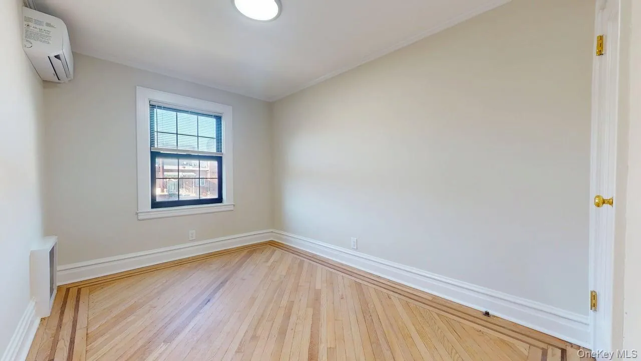 Spare room featuring a wall mounted air conditioner and hardwood / wood-style floors Spare room featuring a wall mounted air conditioner and hardwood / wood-style floors