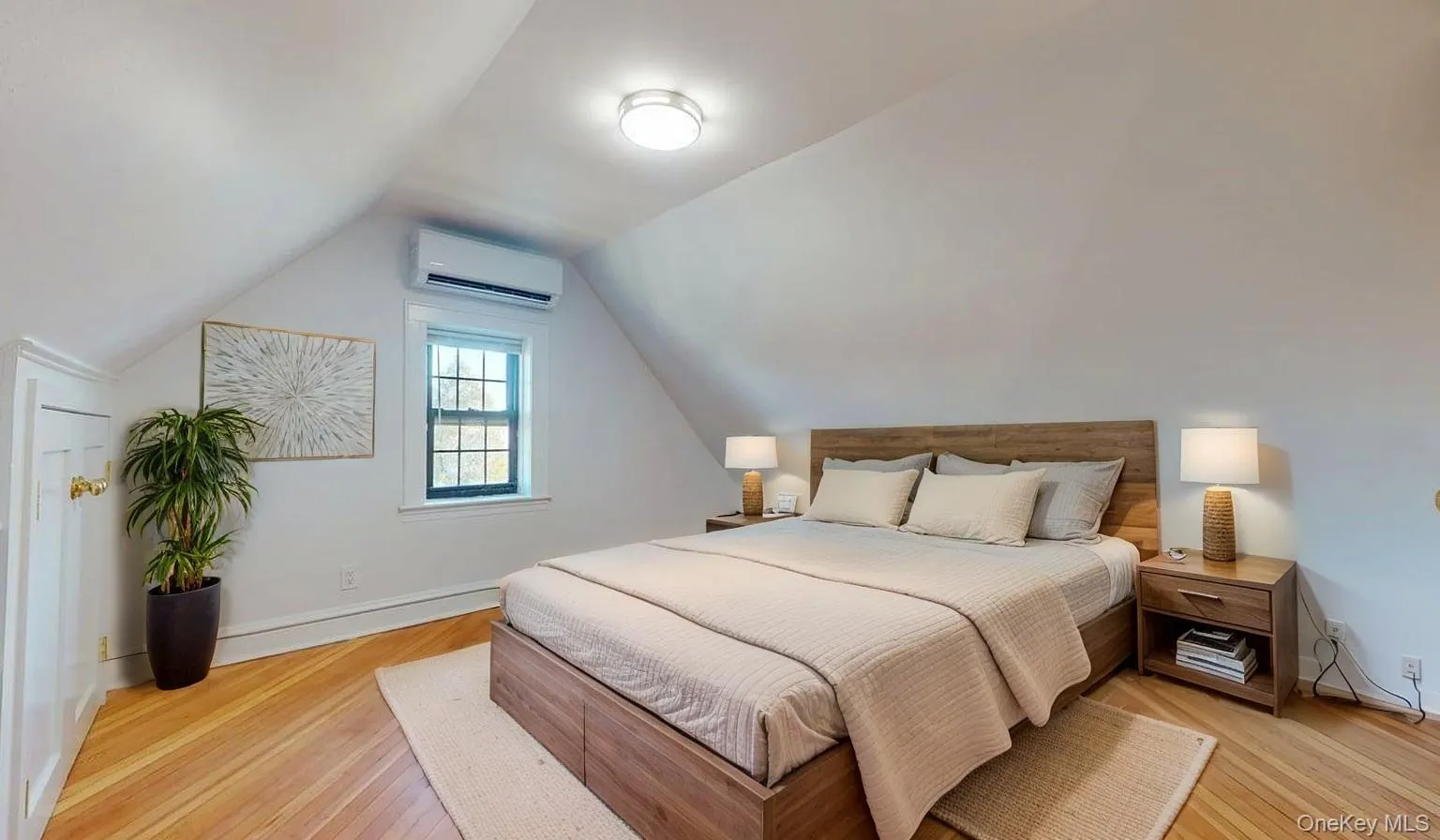 Bedroom featuring vaulted ceiling, a wall mounted AC, and light wood-style floors Bedroom featuring vaulted ceiling, a wall mounted AC, and light wood-style floors