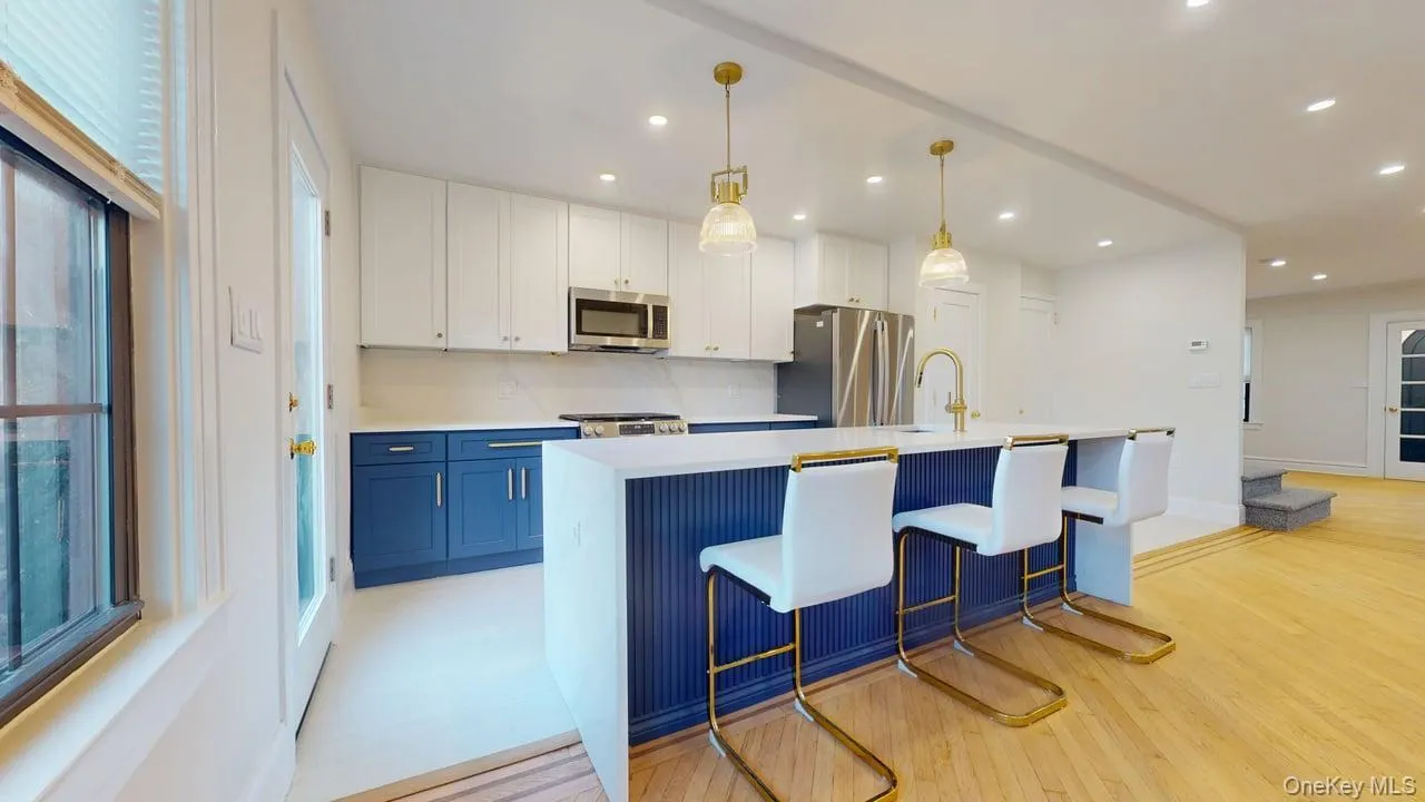 Kitchen with hanging light fixtures, appliances with stainless steel finishes, an island with sink, white cabinetry, and blue cabinets Kitchen with hanging light fixtures, appliances with stainless steel finishes, an island with sink, white cabinetry, and blue cabinets