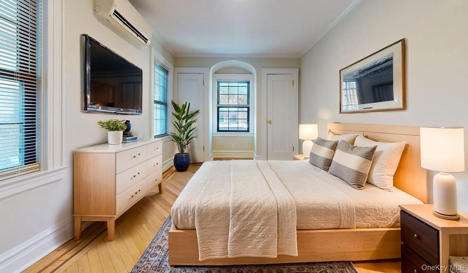 Bedroom featuring a wall mounted AC, light wood-style floors, and ornamental molding Bedroom featuring a wall mounted AC, light wood-style floors, and ornamental molding