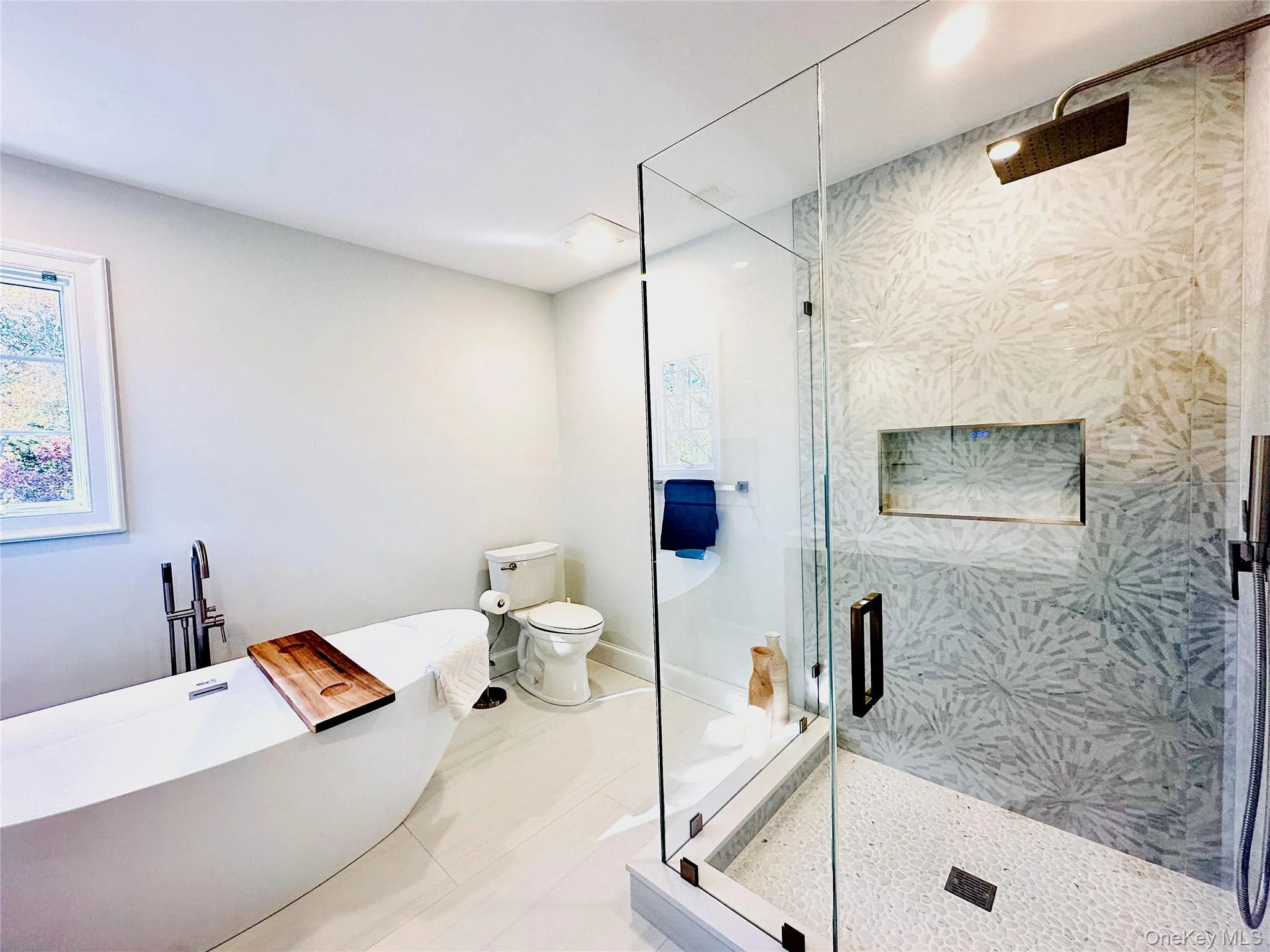 Full bathroom with a freestanding tub, a stall shower, and plenty of natural light Full bathroom with a freestanding tub, a stall shower, and plenty of natural light