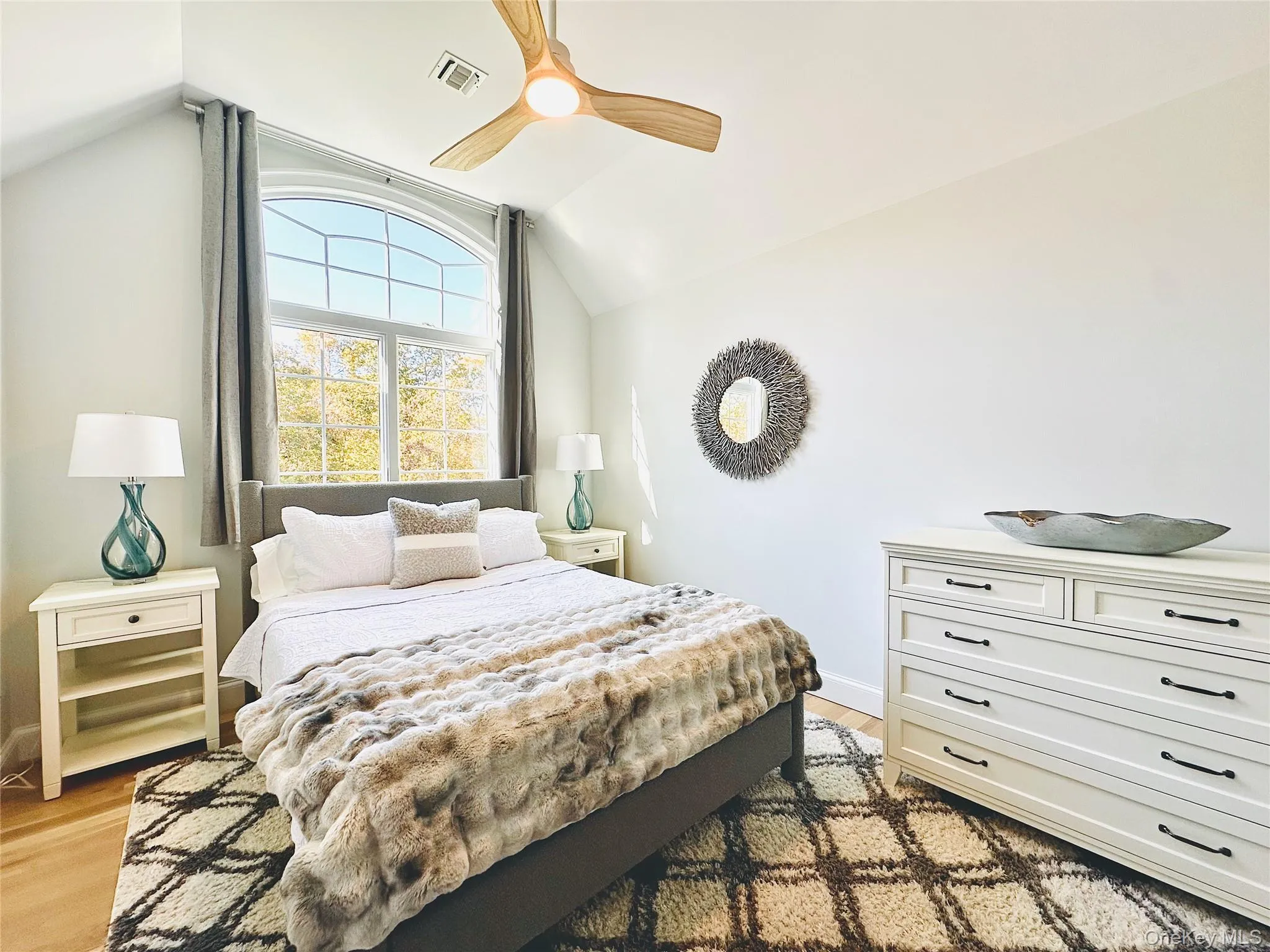 Bedroom with vaulted ceiling, light wood-style flooring, and ceiling fan Bedroom with vaulted ceiling, light wood-style flooring, and ceiling fan