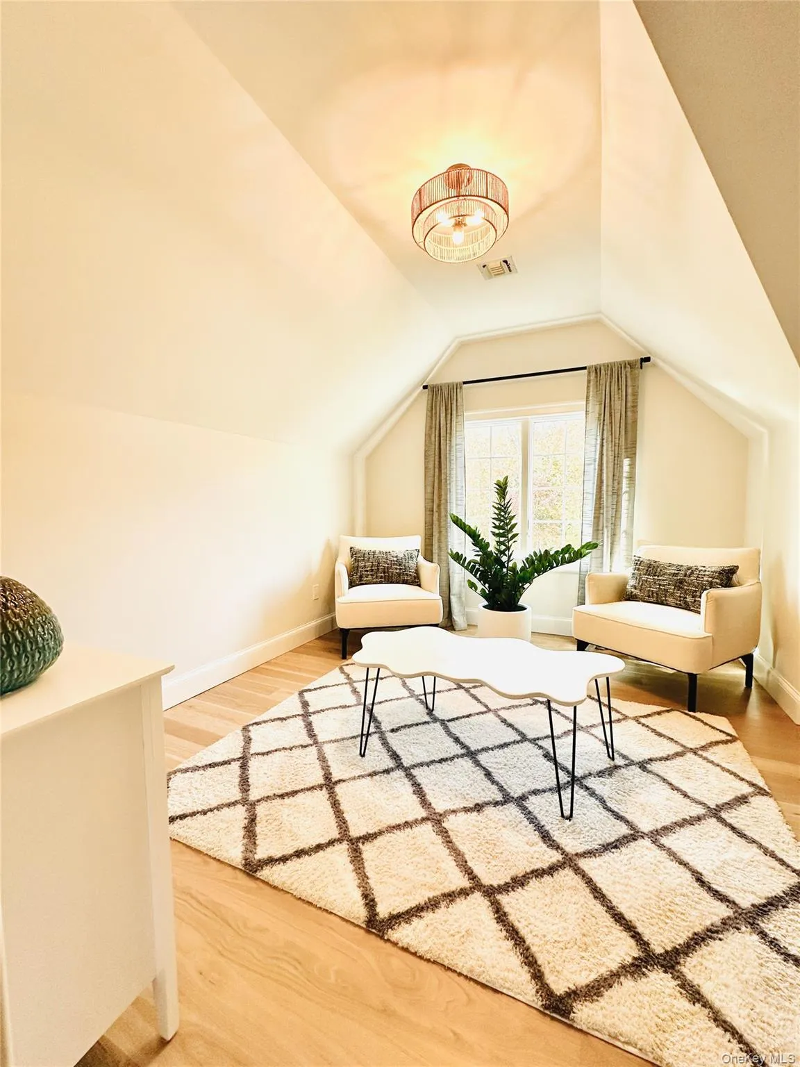 Sitting room with light wood-style floors and vaulted ceiling Sitting room with light wood-style floors and vaulted ceiling