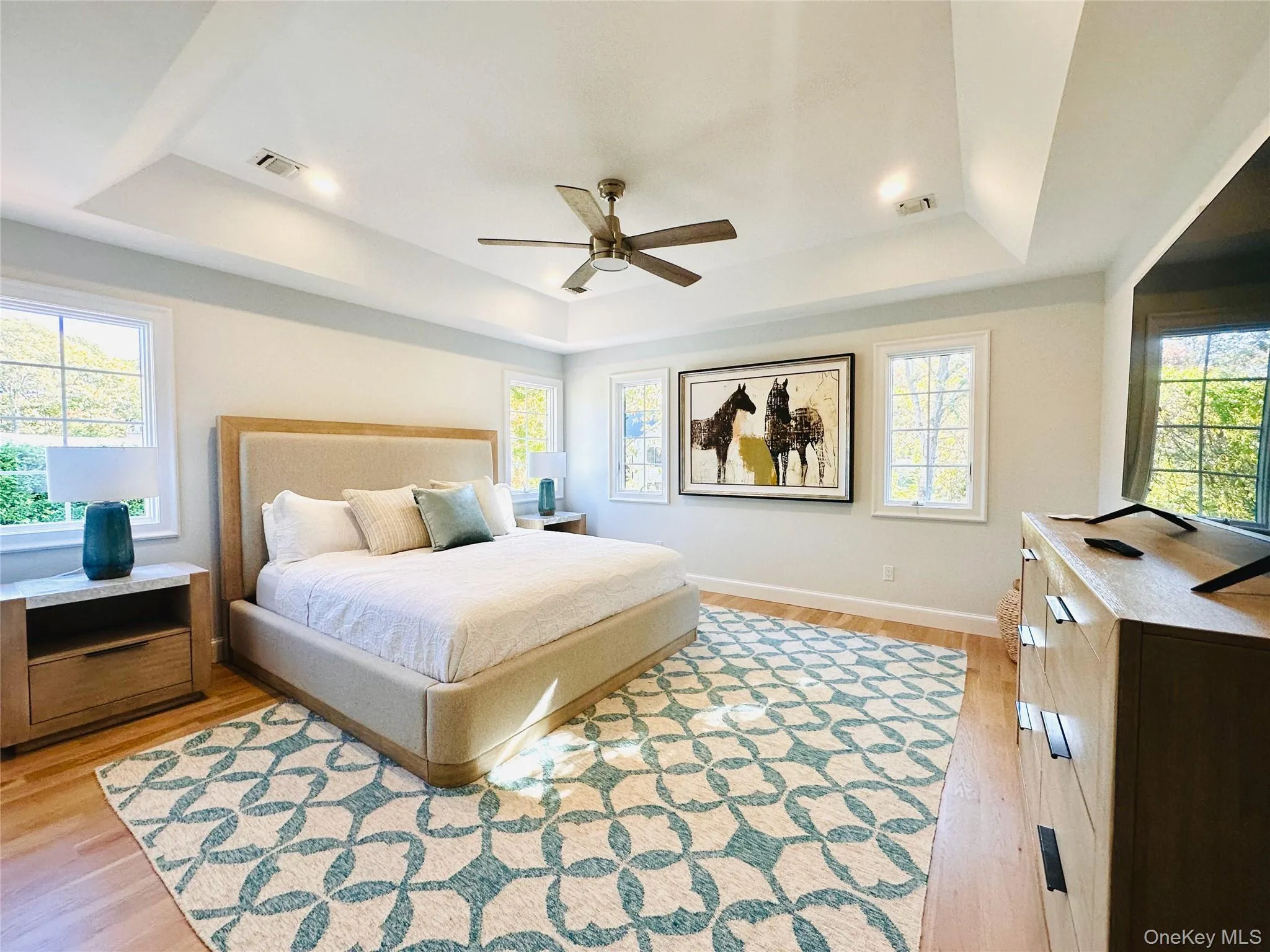 Bedroom featuring a tray ceiling, light wood-style flooring, and ceiling fan Bedroom featuring a tray ceiling, light wood-style flooring, and ceiling fan
