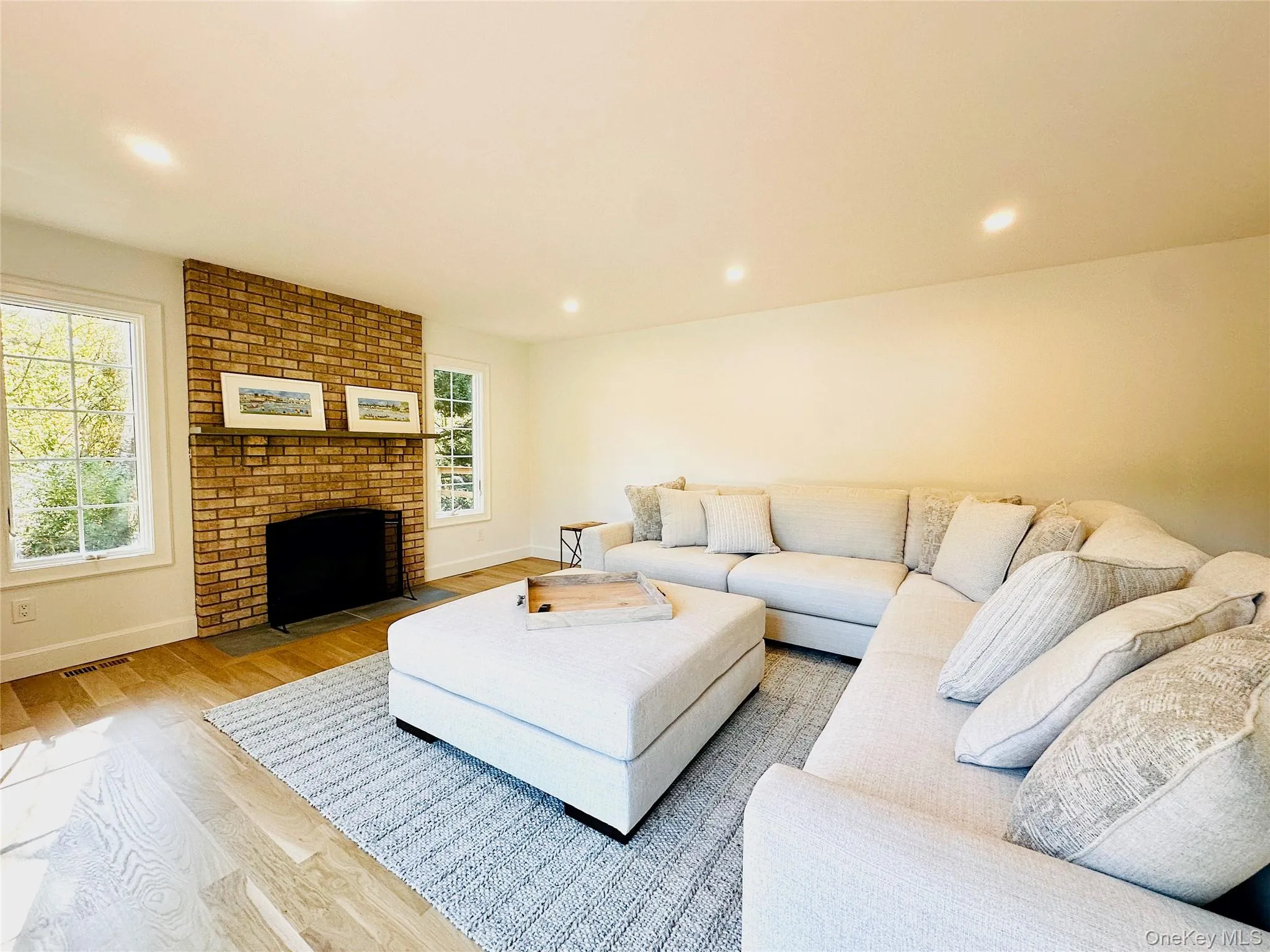 Living room with wood finished floors, a fireplace, and recessed lighting Living room with wood finished floors, a fireplace, and recessed lighting