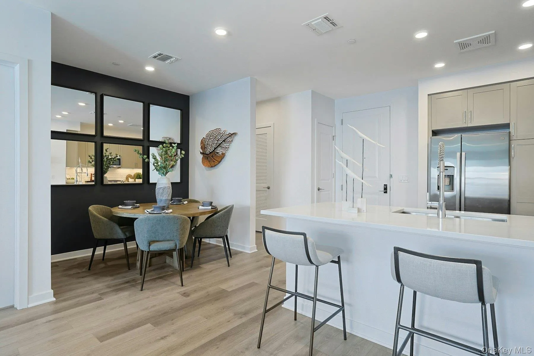 Kitchen featuring stainless steel fridge, a breakfast bar, light wood-type flooring, gray cabinets, and Quartz countertops Kitchen featuring stainless steel fridge, a breakfast bar, light wood-type flooring, gray cabinets, and Quartz countertops