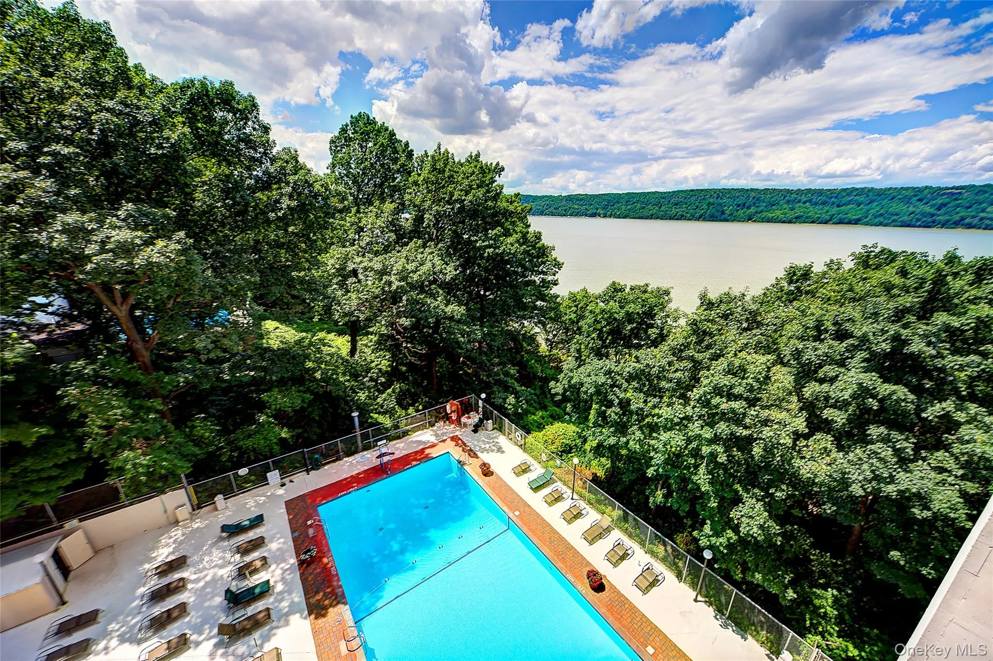 Community pool with a forest view, a patio, and a water view Community pool with a forest view, a patio, and a water view