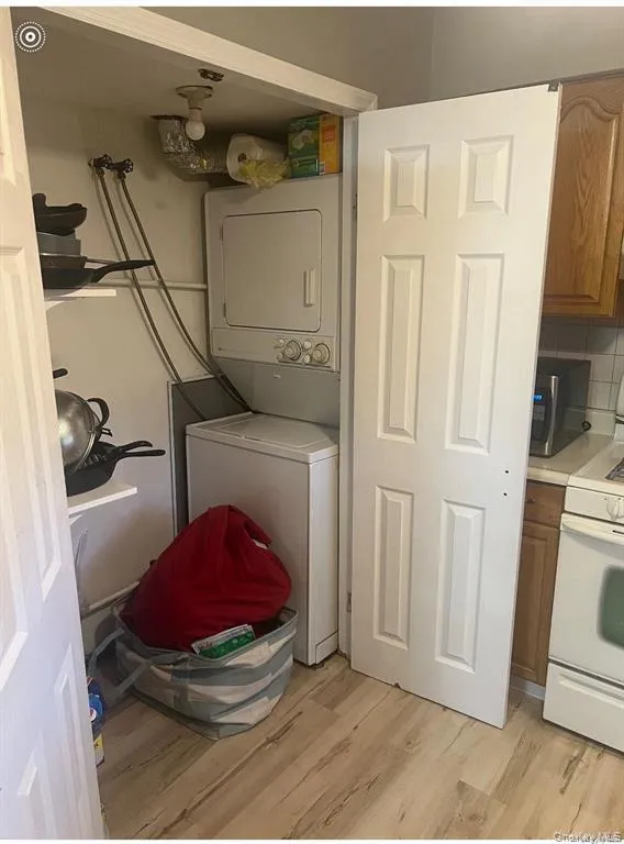 Laundry room featuring light wood-style flooring and stacked washer / drying machine Laundry room featuring light wood-style flooring and stacked washer / drying machine