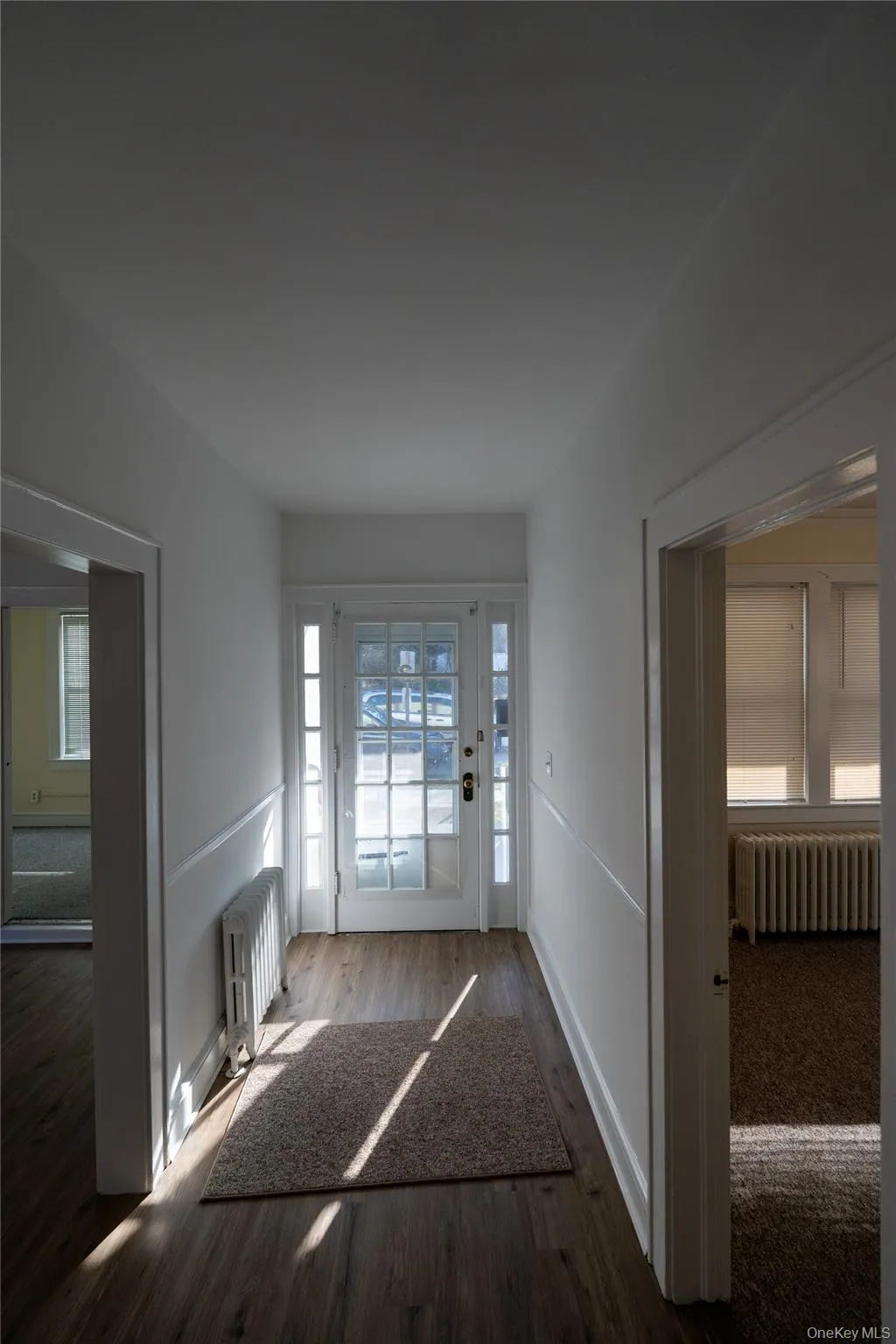 Entryway featuring radiator heating unit, plenty of natural light, and wood finished floors Entryway featuring radiator heating unit, plenty of natural light, and wood finished floors