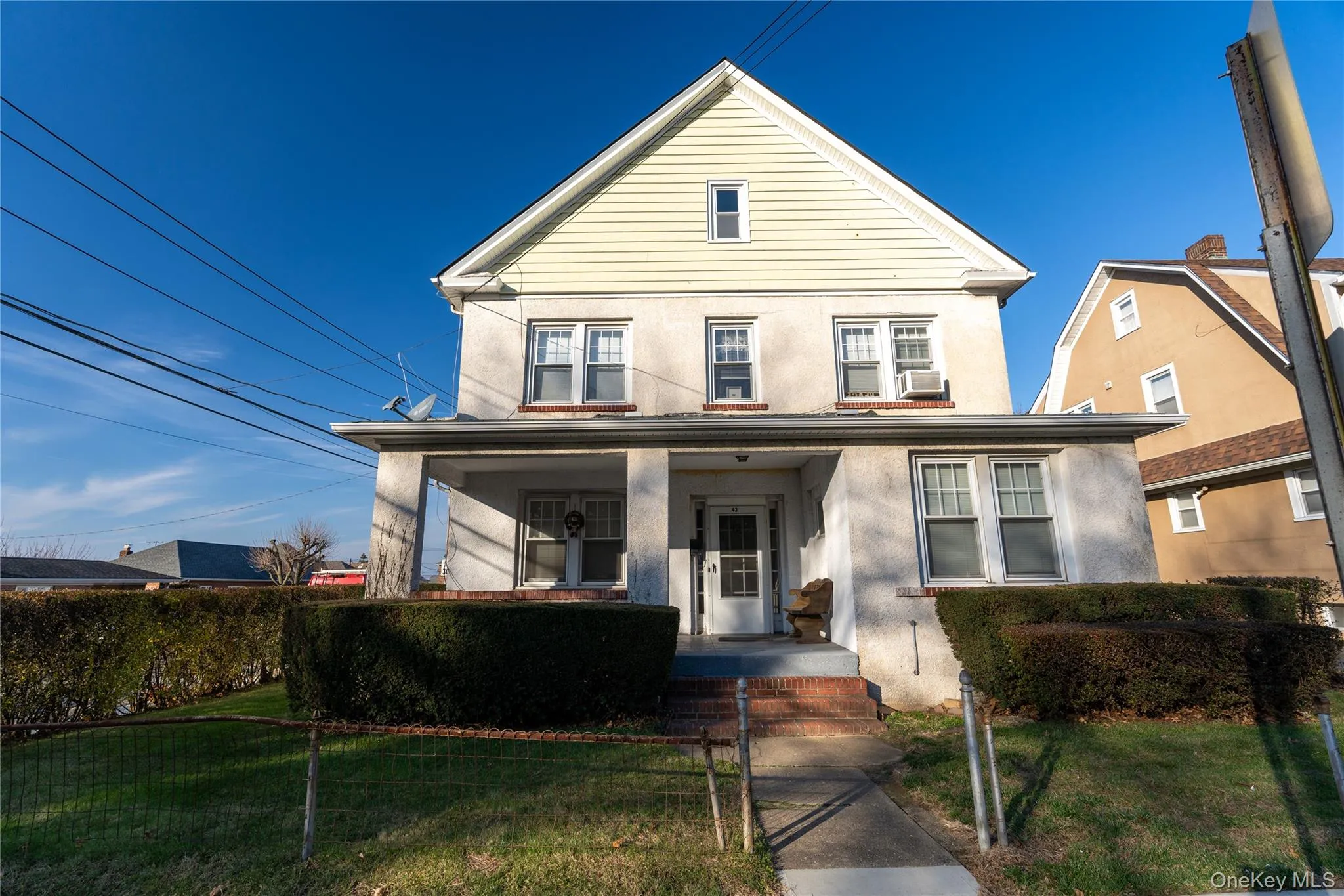 Traditional home featuring a front lawn, stucco siding, and a porch Traditional home featuring a front lawn, stucco siding, and a porch