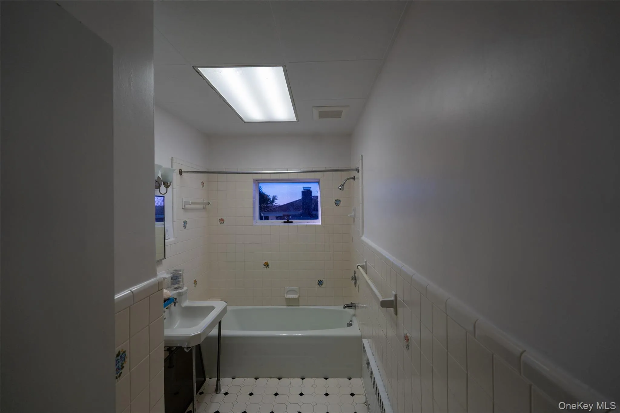 Full bathroom with wainscoting, bathing tub / shower combination, and tile walls Full bathroom with wainscoting, bathing tub / shower combination, and tile walls