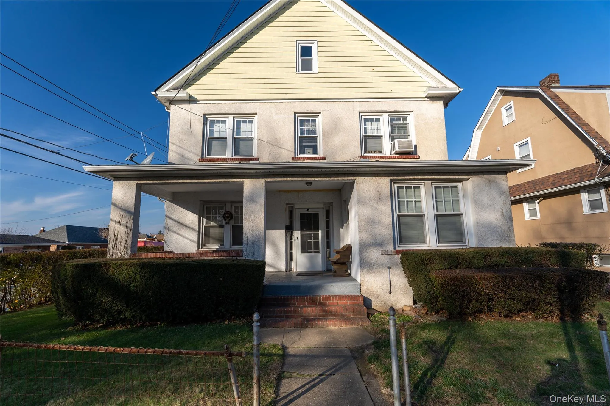 Traditional-style house featuring a front yard, covered porch, and stucco siding Traditional-style house featuring a front yard, covered porch, and stucco siding
