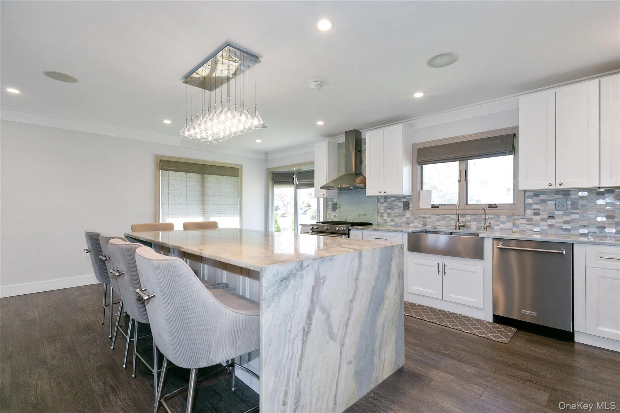 Kitchen featuring a breakfast bar area, light stone countertops, white cabinets, decorative backsplash, and appliances with stainless steel finishes Kitchen featuring a breakfast bar area, light stone countertops, white cabinets, decorative backsplash, and appliances with stainless steel finishes