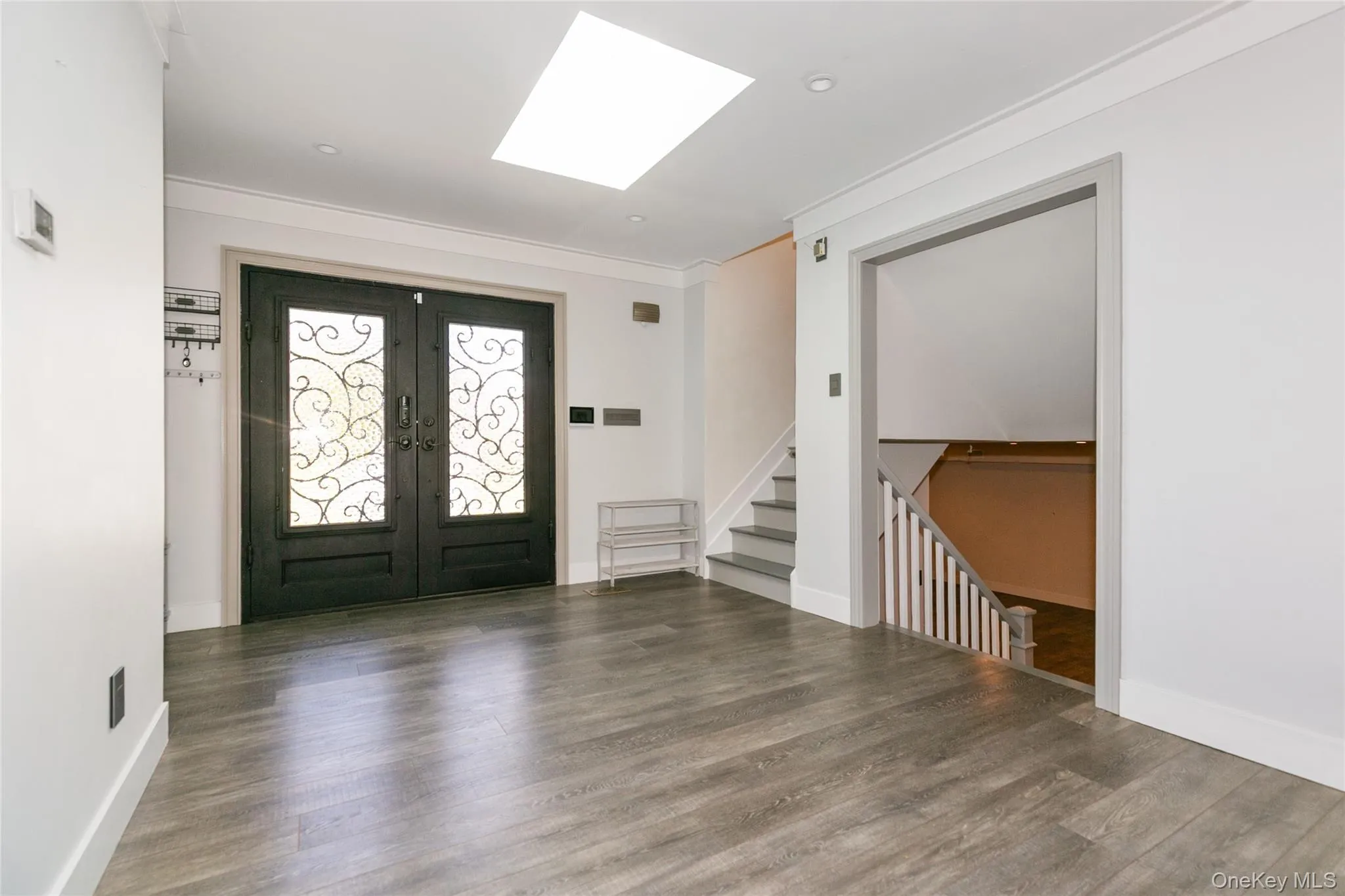 Entryway with crown molding, french doors, a skylight, wood finished floors, and stairway Entryway with crown molding, french doors, a skylight, wood finished floors, and stairway