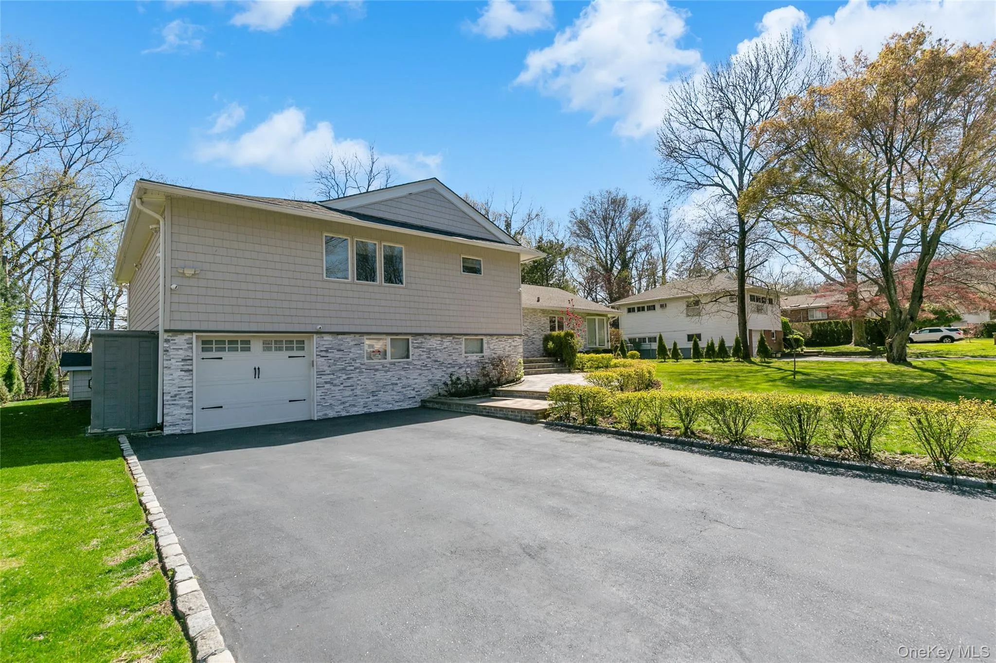 View of property exterior featuring stone siding, a yard, asphalt driveway, and a garage View of property exterior featuring stone siding, a yard, asphalt driveway, and a garage