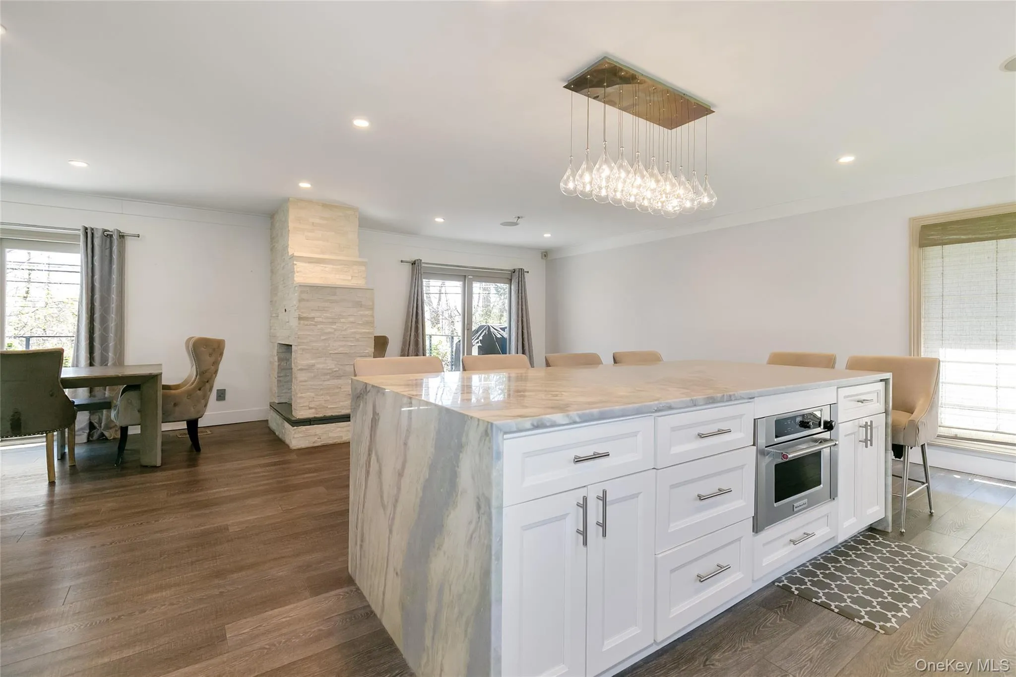 Kitchen featuring a kitchen breakfast bar, light stone countertops, white cabinetry, stainless steel oven, and ornamental molding Kitchen featuring a kitchen breakfast bar, light stone countertops, white cabinetry, stainless steel oven, and ornamental molding