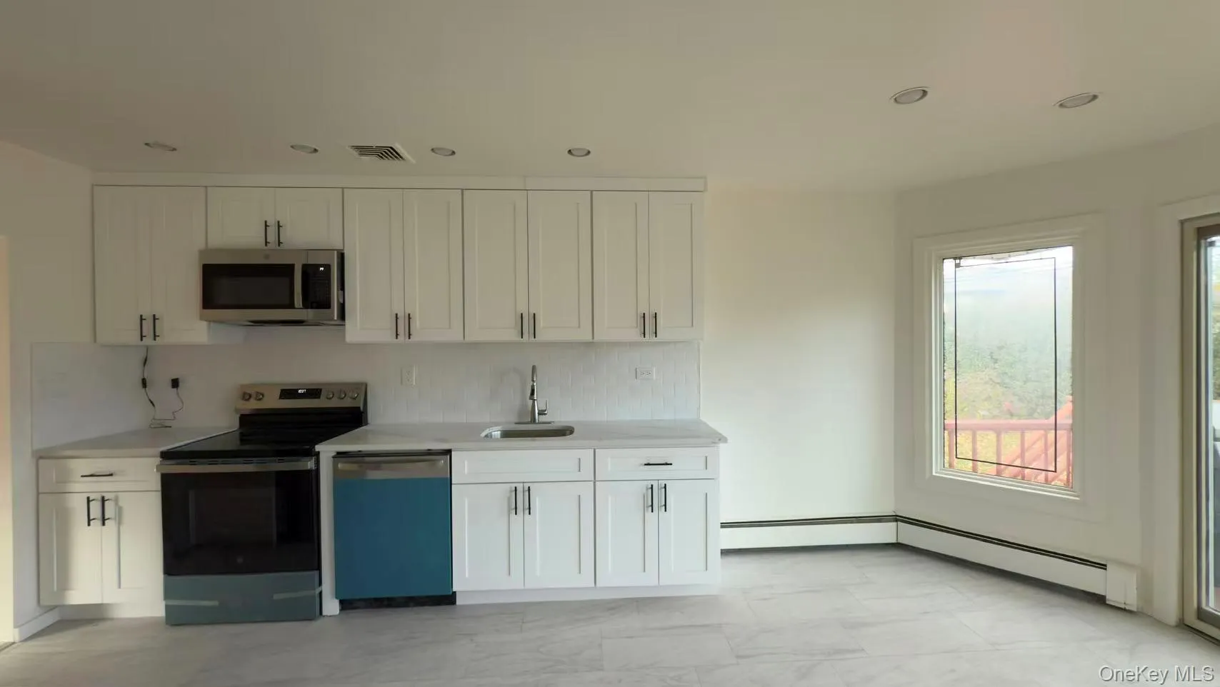 Kitchen featuring appliances with stainless steel finishes, decorative backsplash, white cabinetry, recessed lighting, and light stone counters Kitchen featuring appliances with stainless steel finishes, decorative backsplash, white cabinetry, recessed lighting, and light stone counters