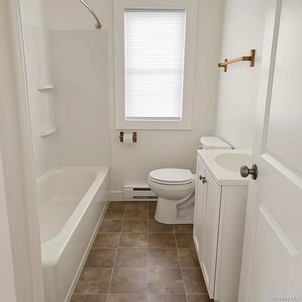 Full bath with vanity, baseboard heating, dark tile patterned flooring, and tub / shower combination Full bath with vanity, baseboard heating, dark tile patterned flooring, and tub / shower combination