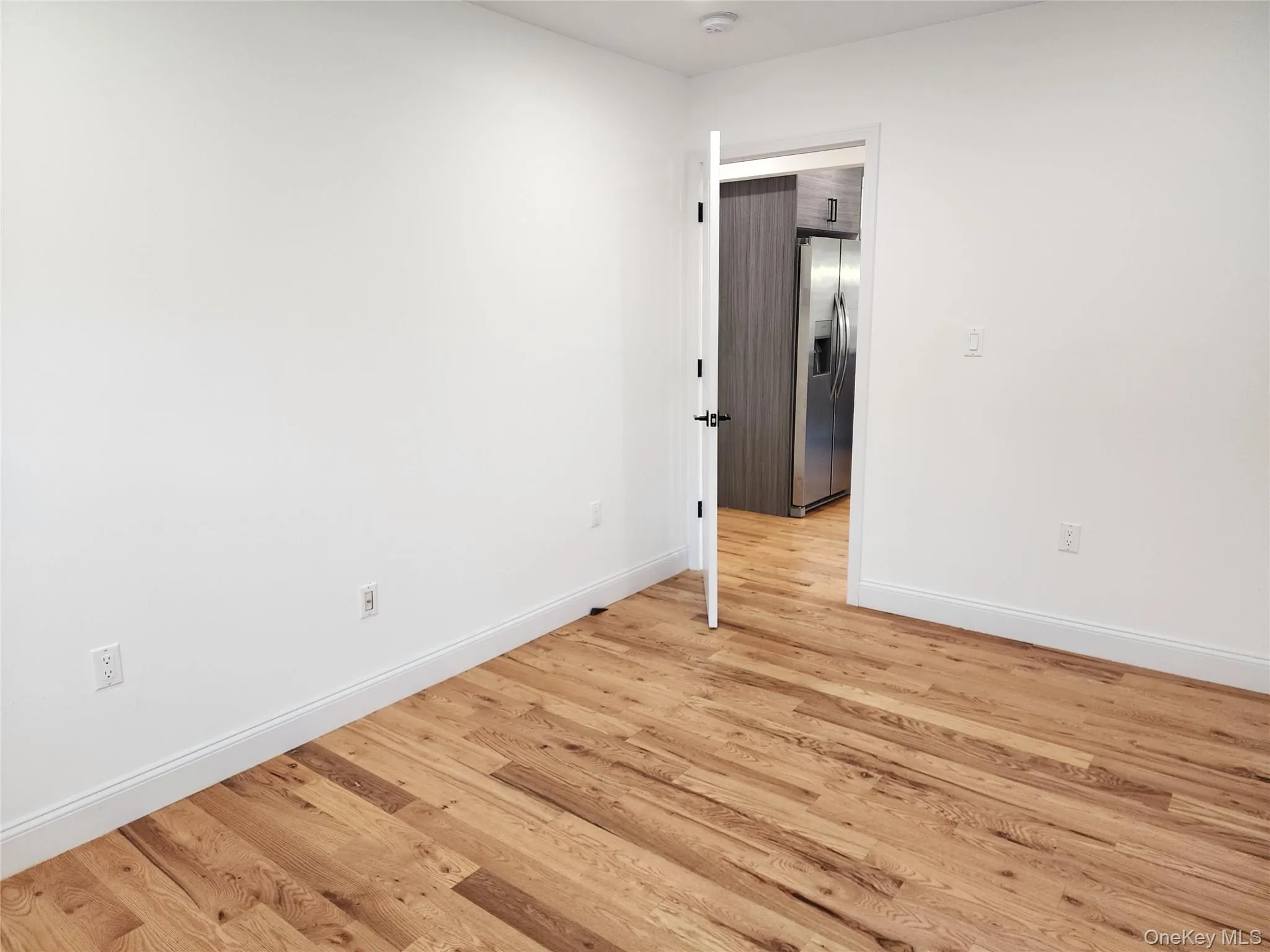 Spare room featuring baseboards and light wood-style floors Spare room featuring baseboards and light wood-style floors