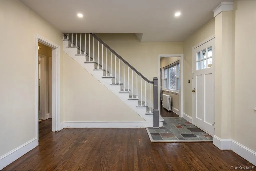 Entryway featuring dark wood-style floors, stairway, radiator, and recessed lighting Entryway featuring dark wood-style floors, stairway, radiator, and recessed lighting