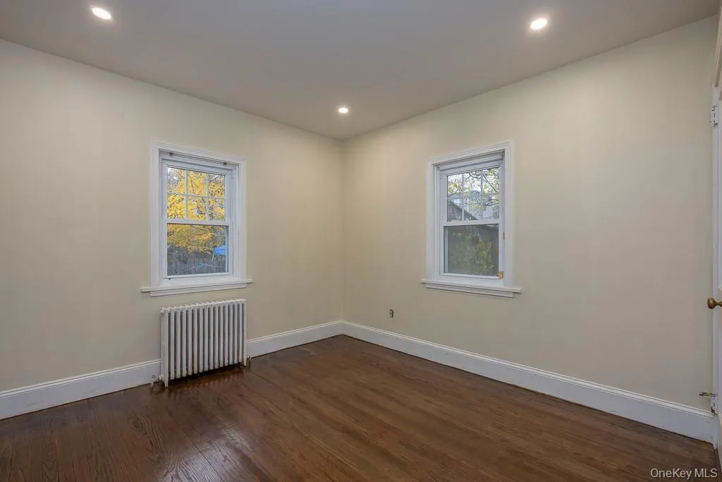 Unfurnished room featuring radiator heating unit, dark wood finished floors, and recessed lighting Unfurnished room featuring radiator heating unit, dark wood finished floors, and recessed lighting