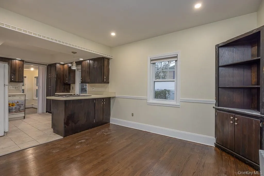 Kitchen featuring dark brown cabinetry, a peninsula, light countertops, light wood-style flooring, and recessed lighting Kitchen featuring dark brown cabinetry, a peninsula, light countertops, light wood-style flooring, and recessed lighting