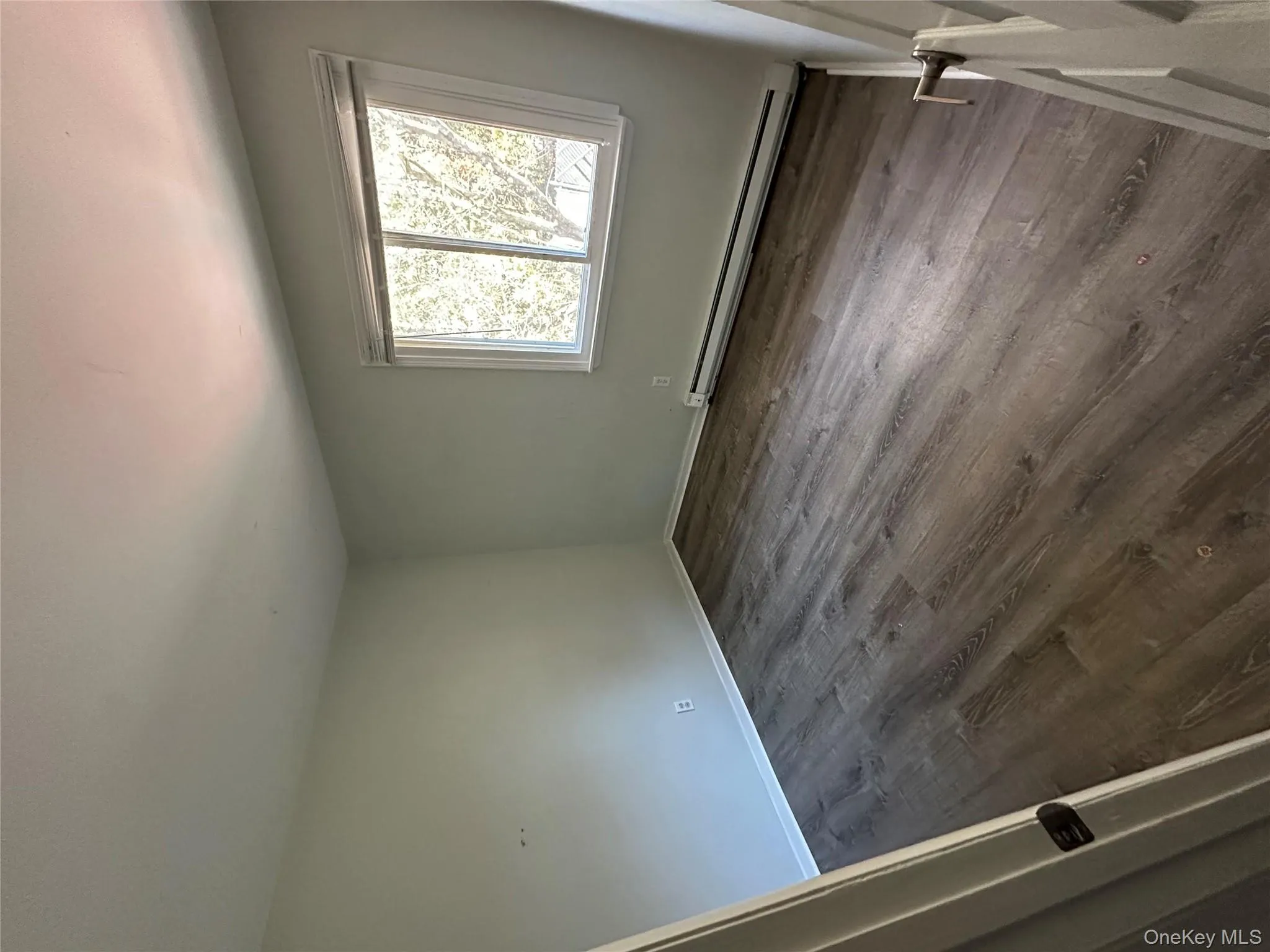 Spare room featuring baseboard heating and dark wood-type flooring Spare room featuring baseboard heating and dark wood-type flooring