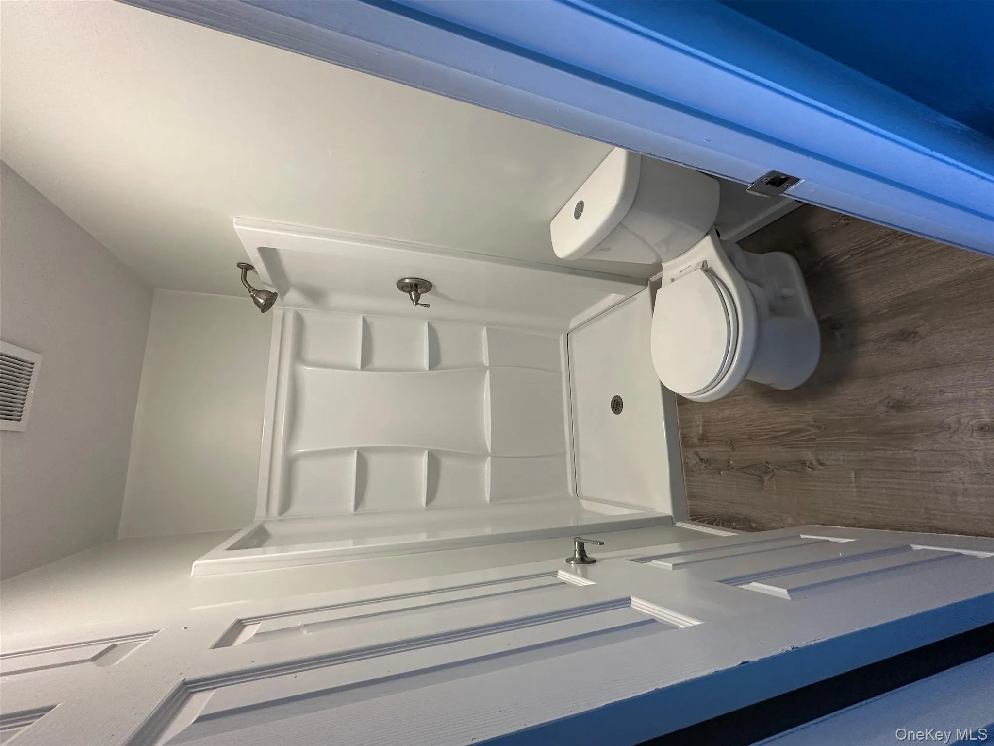 Bathroom featuring dark wood-style floors and a stall shower Bathroom featuring dark wood-style floors and a stall shower