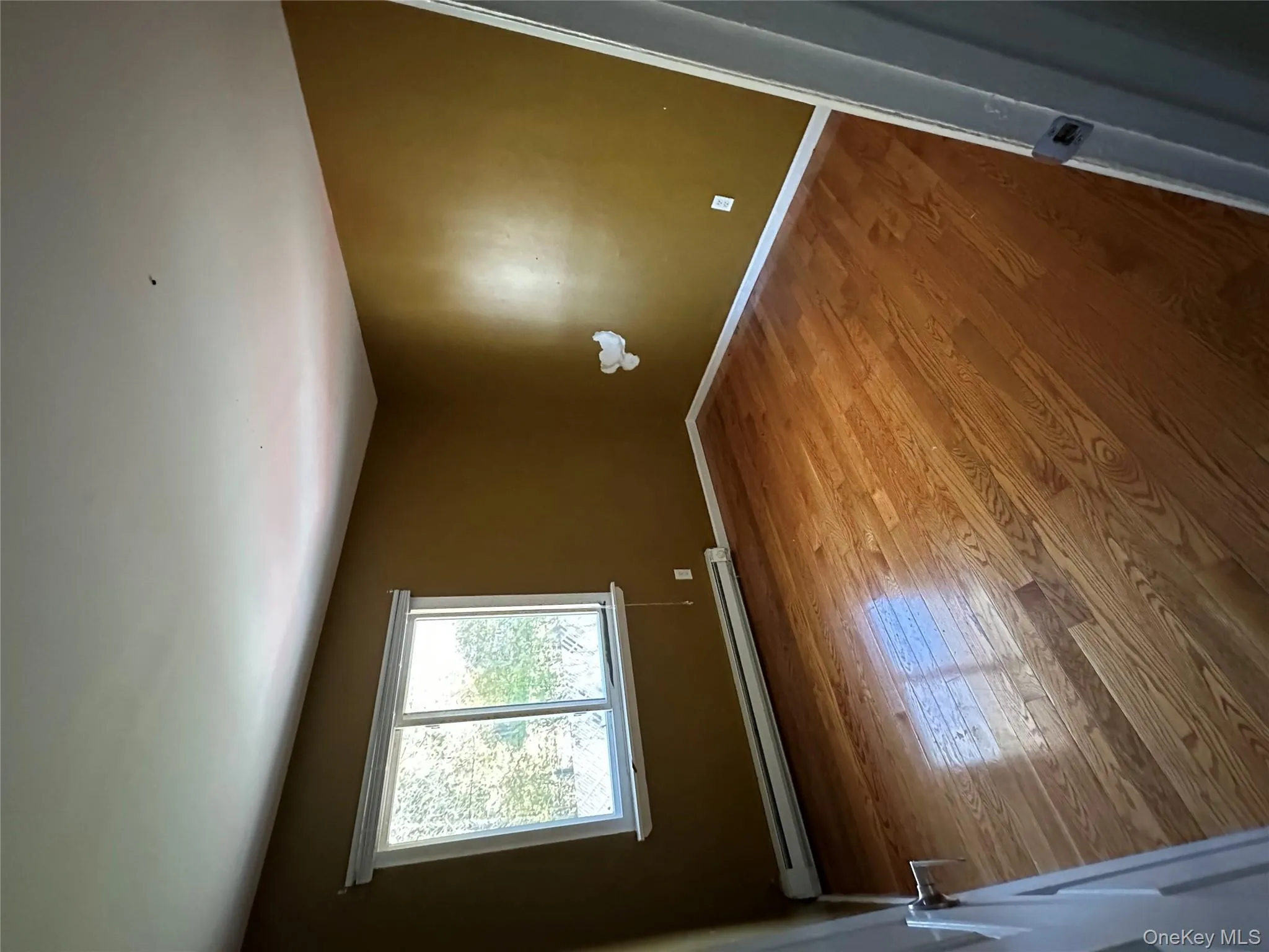 Unfurnished room with a baseboard radiator and hardwood / wood-style flooring Unfurnished room with a baseboard radiator and hardwood / wood-style flooring