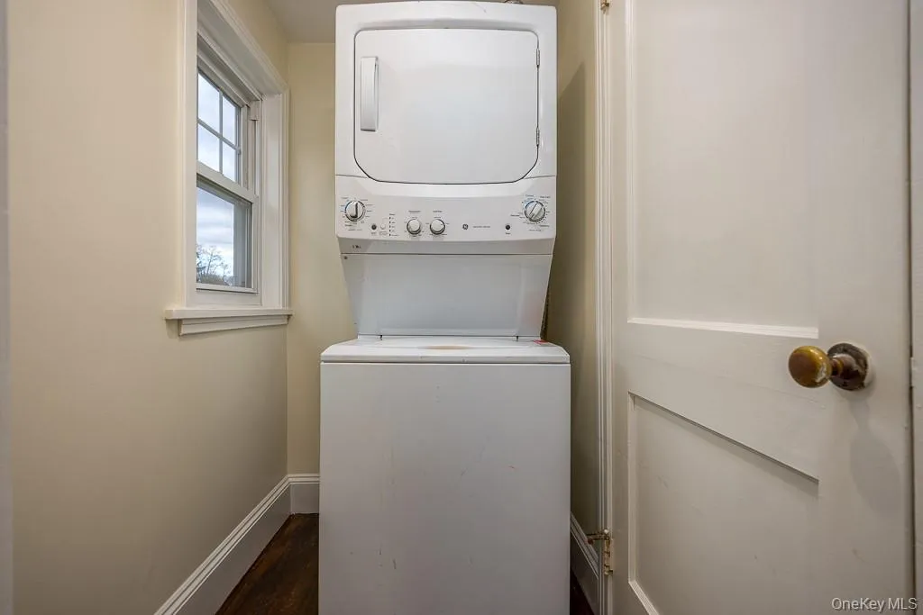 Laundry room featuring dark wood-style floors and stacked washer and clothes dryer Laundry room featuring dark wood-style floors and stacked washer and clothes dryer