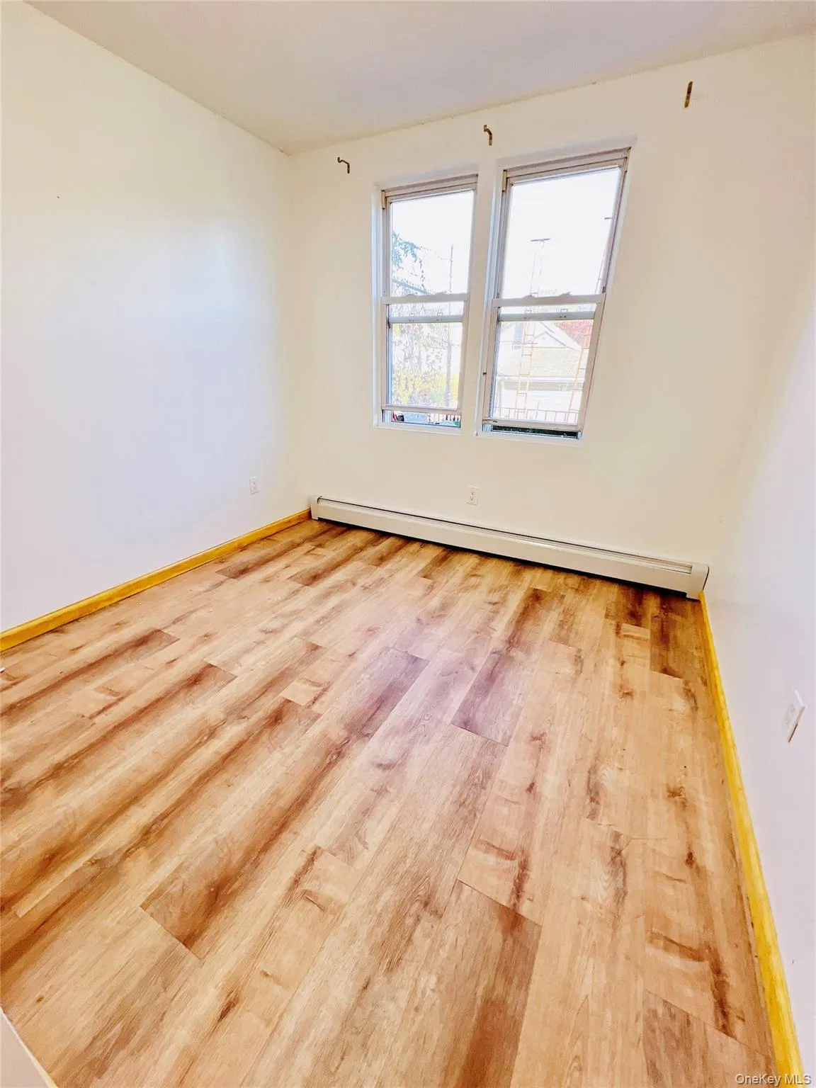Empty room with a baseboard radiator and light wood-style flooring Empty room with a baseboard radiator and light wood-style flooring