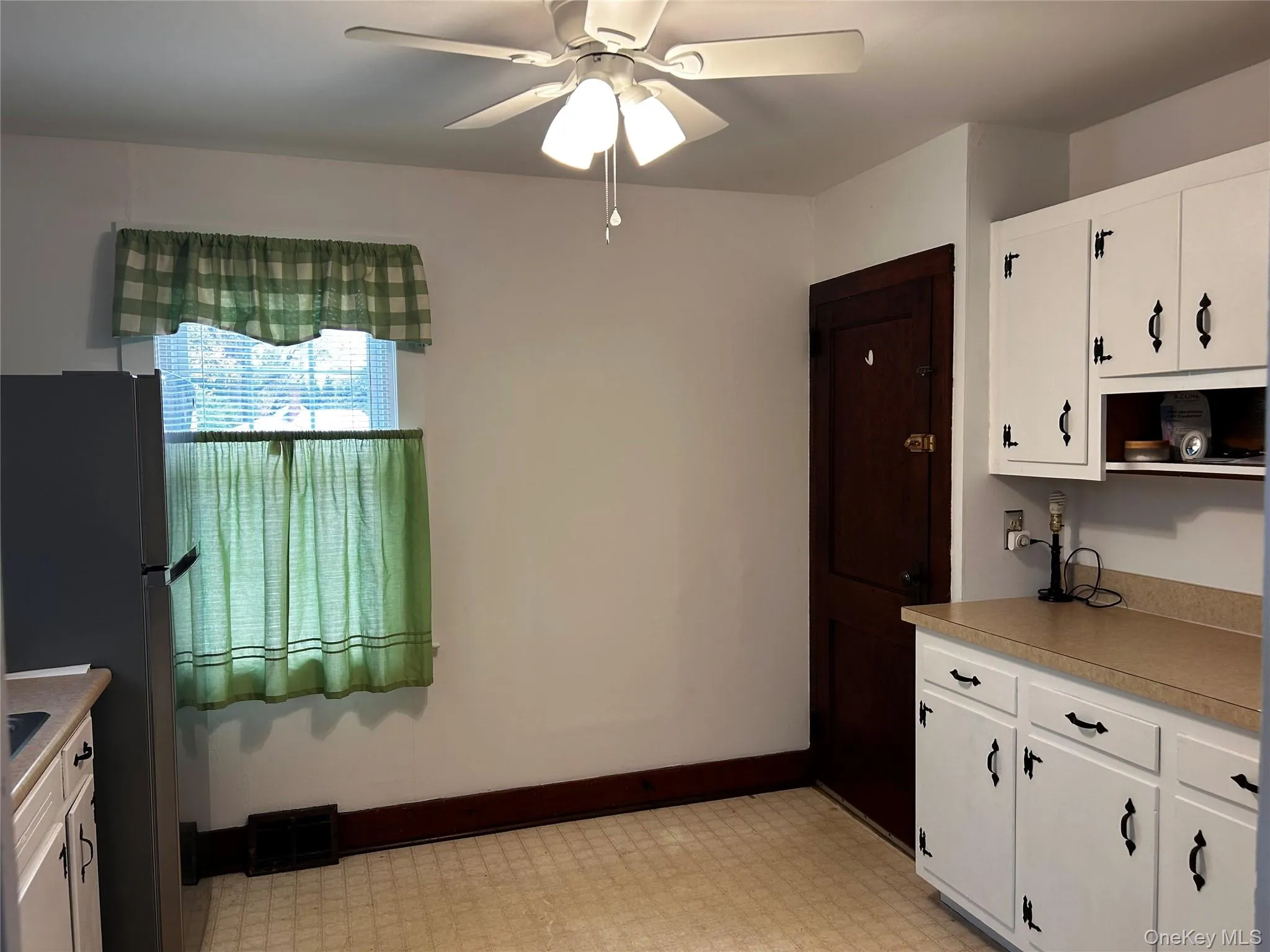 Kitchen with white cabinets, new freestanding stainless steel refrigerator, light countertops, and light floors Kitchen with white cabinets, new freestanding stainless steel refrigerator, light countertops, and light floors