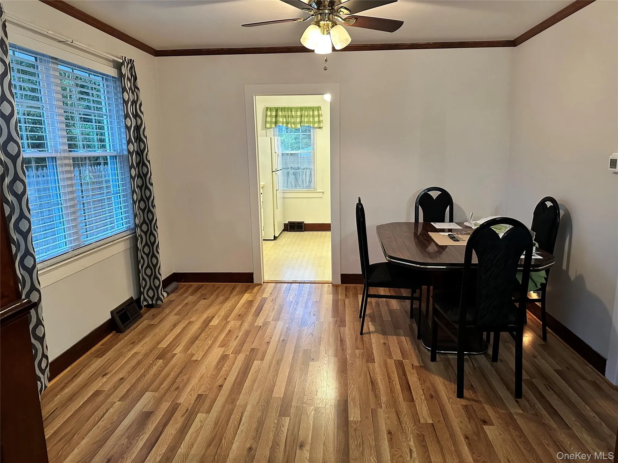 Dining space featuring crown molding, wood finished floors, and a ceiling fan Dining space featuring crown molding, wood finished floors, and a ceiling fan