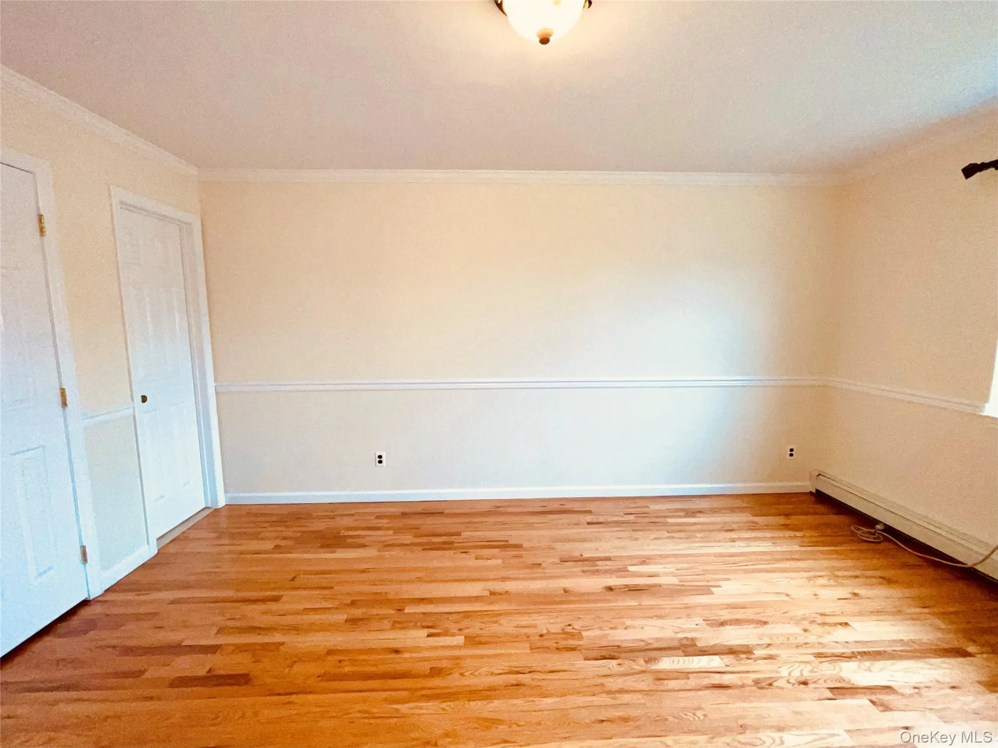 Unfurnished bedroom featuring light wood-type flooring and ornamental molding Unfurnished bedroom featuring light wood-type flooring and ornamental molding