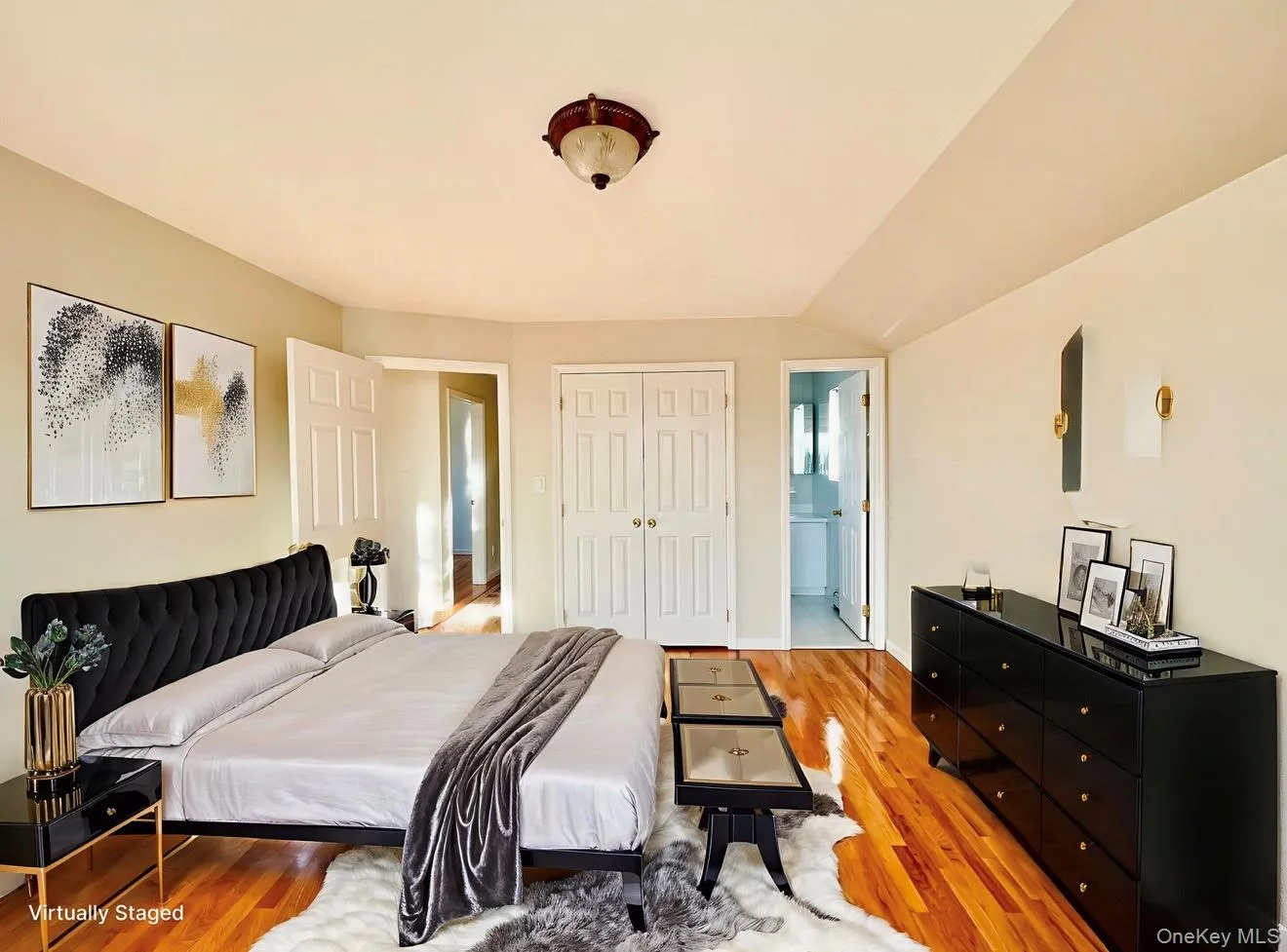 Bedroom featuring wood finished floors, a closet, ensuite bath, and lofted ceiling Bedroom featuring wood finished floors, a closet, ensuite bath, and lofted ceiling