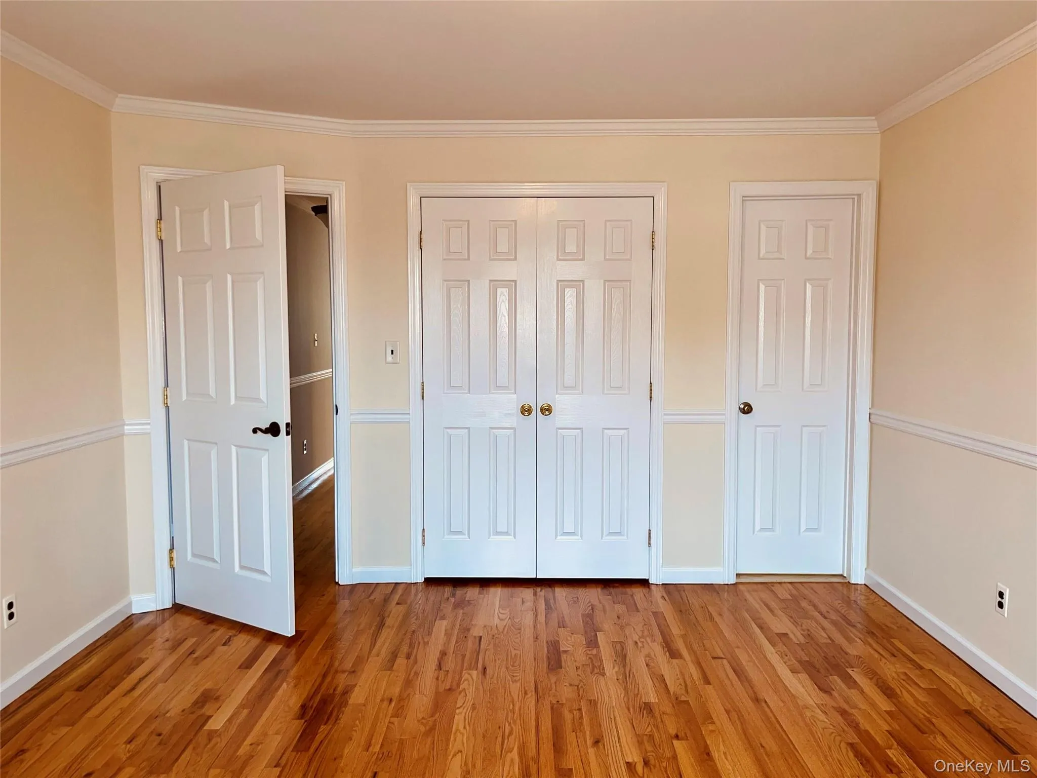 Unfurnished bedroom featuring crown molding, wood finished floors, and a closet Unfurnished bedroom featuring crown molding, wood finished floors, and a closet